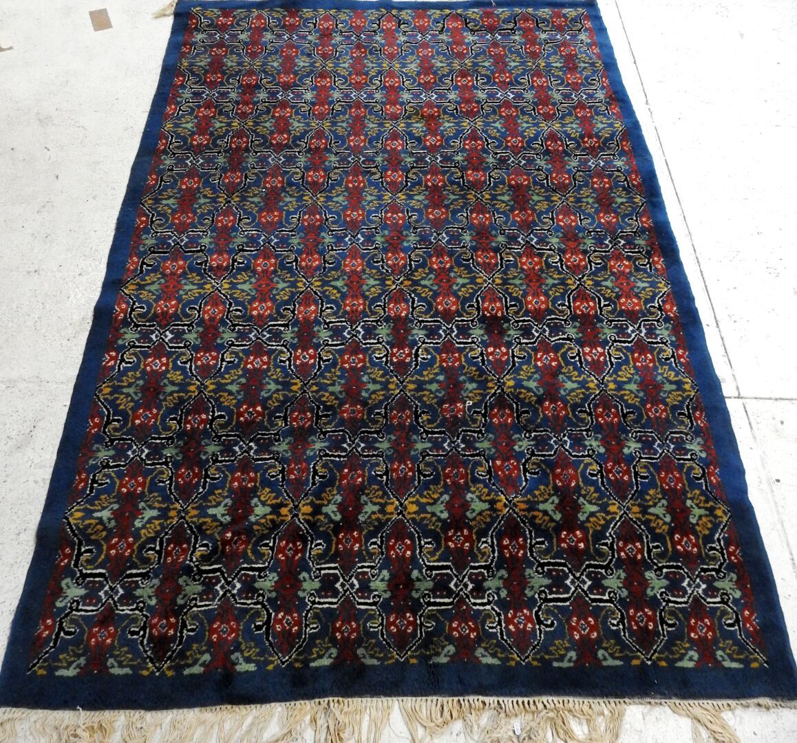 Null 长方形的羊毛地毯，蓝色背景上有红色、绿色和黄色的几何装饰。

约264 x 184厘米。

磨损和撕裂。
