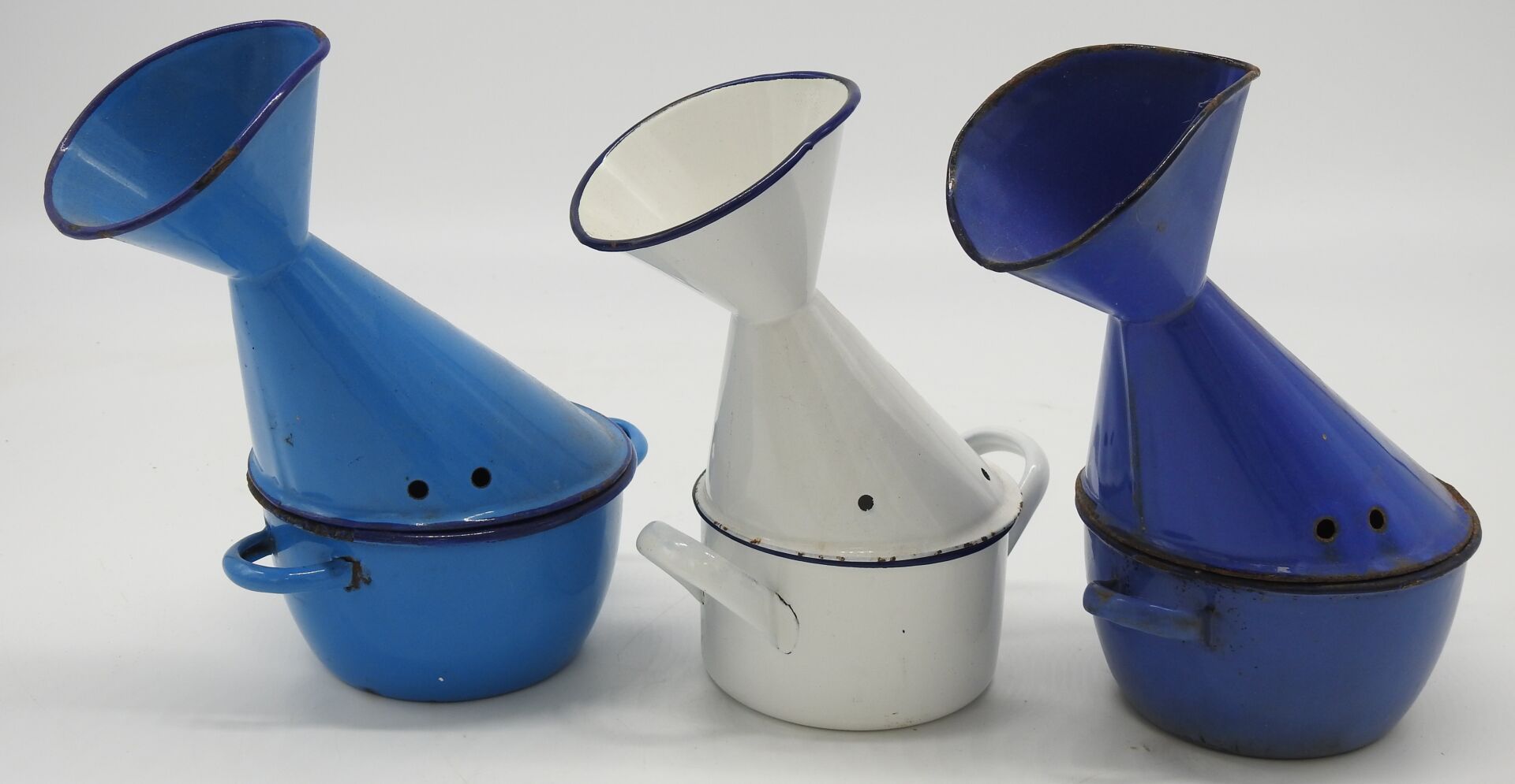 Null 一组搪瓷容器包括：:

三个珐琅金属吸入器，其中两个是蓝色的，一个是有蓝色边框的白色。按原样。

一件白色珐琅彩圆筒锅，带有蓝色管道。高11,5 x &hellip;