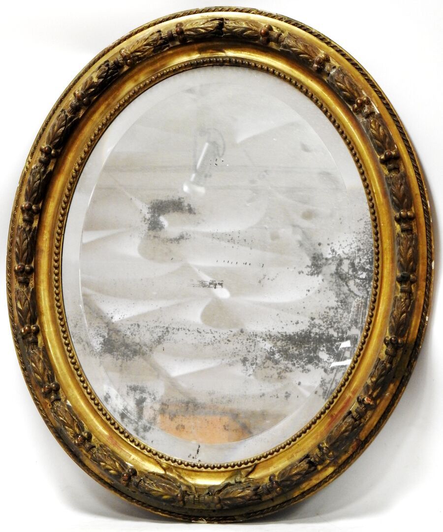 Null 
一面路易十六风格的椭圆形斜面镜子，用木头和镀金灰泥装饰有珍珠和月桂树叶的楣。




19世纪时期。




92,5 x 74,5厘米。




&hellip;