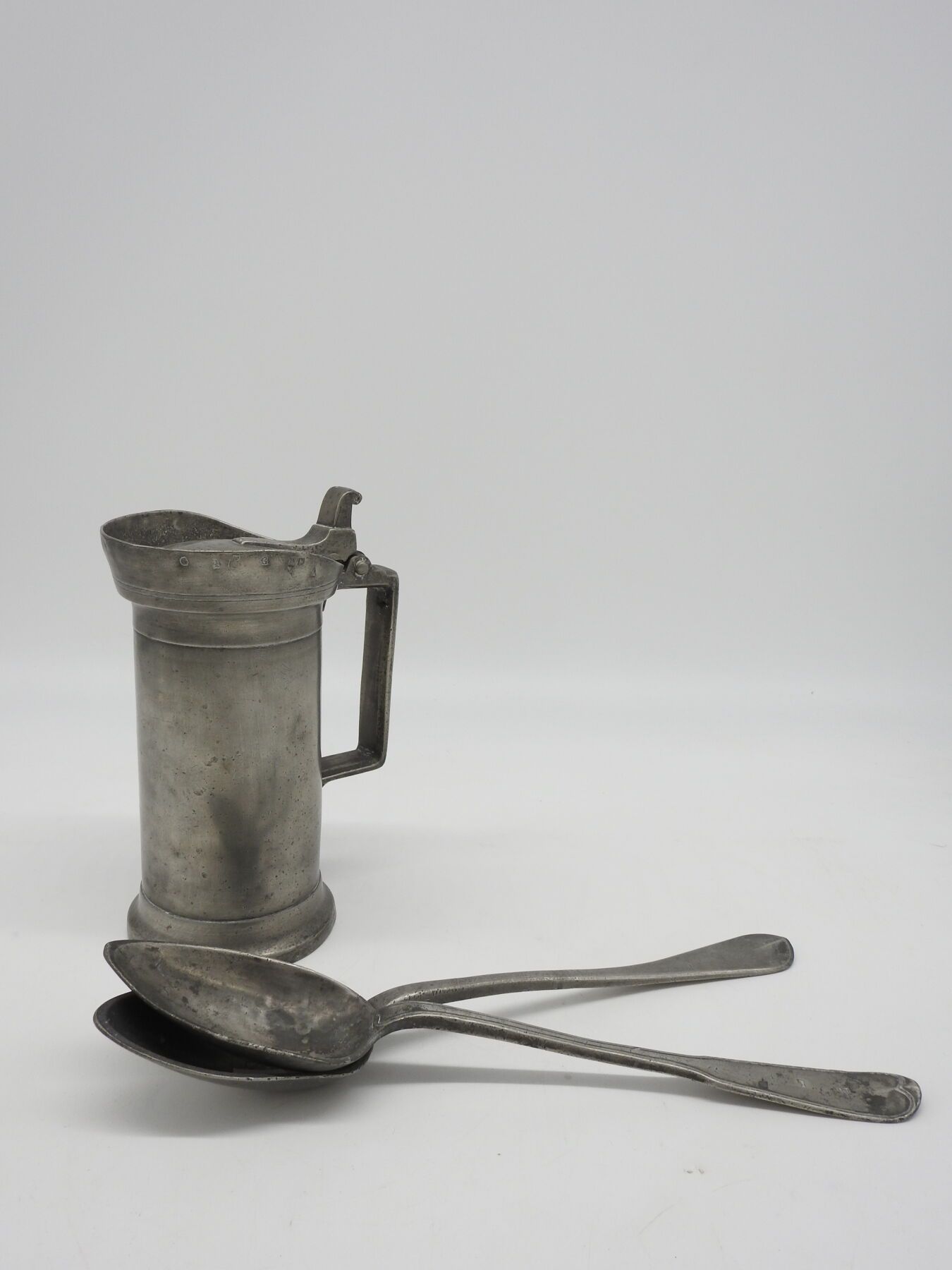 Null ETAIN : Two ragout spoons (Paris) and a measuring jug. H : 23 cm.