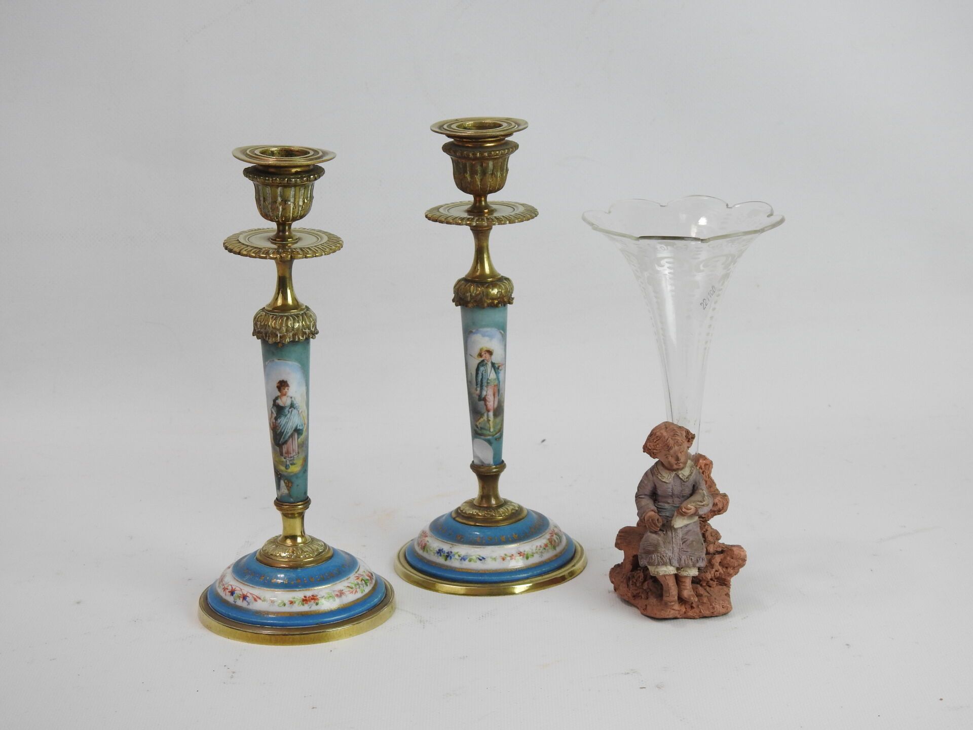 Null 拍品包括一个吹制和雕刻的玻璃角花瓶和一个多色陶土框架，显示一个孩子在长凳上阅读。约1900年。H. 19厘米。一对巴黎瓷器烛台，青铜支架（口）。