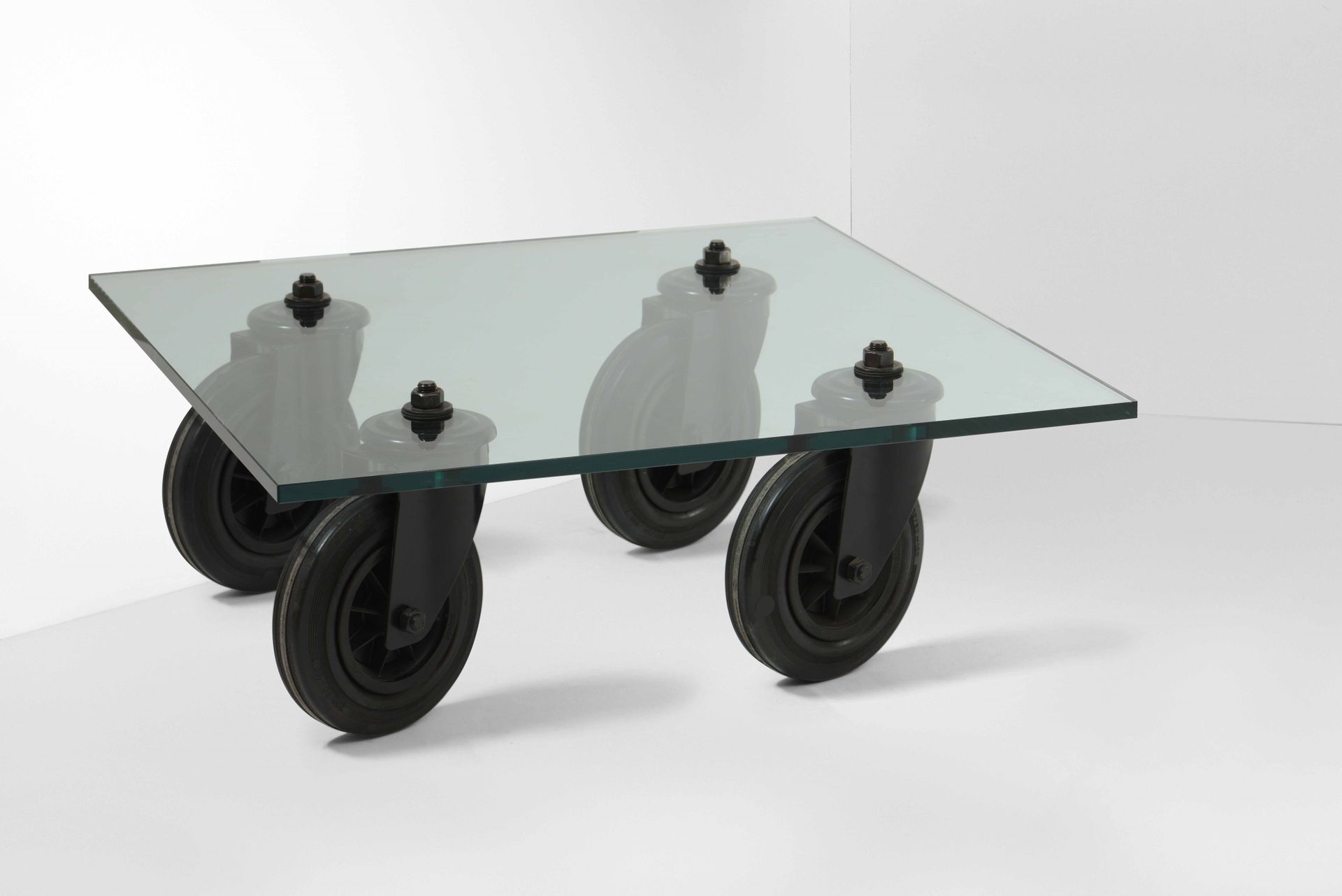 Gae Aulenti, Low table with bevelled crystal top. Lacquered metal wheel supports&hellip;