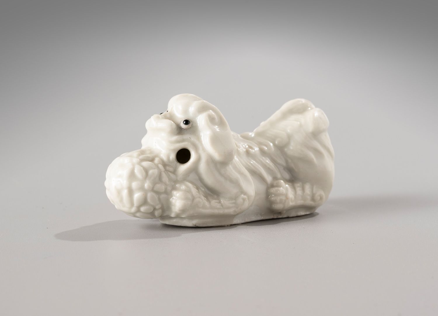 Null 中国，康熙时期，18世纪

中国白瓷笔架。

代表着一只躺着的狮子，它的爪子拿着神圣的

拿着神圣的珠宝。

长8厘米。

底座上有Wanieck标签&hellip;
