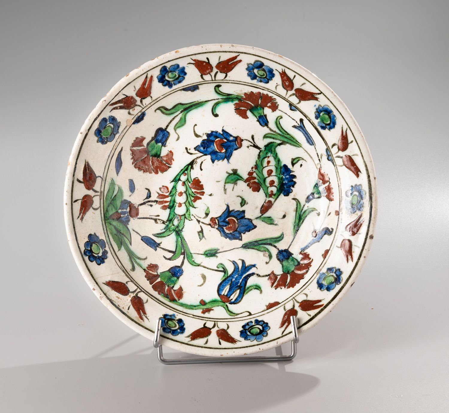 Null IZNIK

带铅釉的圆形硅质陶瓷盘

带有棕榈树、康乃馨、郁金香的多色装饰。

17世纪

D. 28,5cm。

(碎成几块，事故和修复）。)