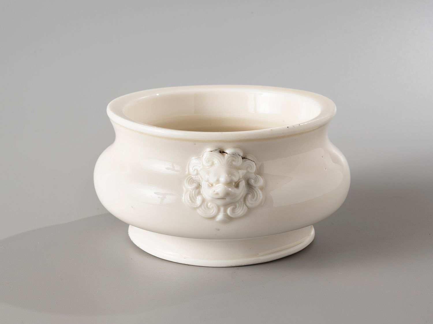 Null 中国，康熙时期，18世纪

白瓷香炉，饰以

两个狮子头形状的把手。马克

基地上的成语。

最大直径15.5厘米

(内部缺少一个元件，手柄附近有两&hellip;
