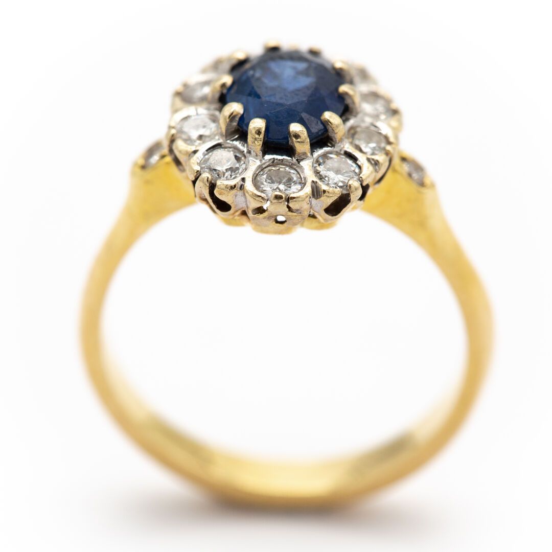 Null 18K黄金雏菊戒指，镶嵌着一颗椭圆形的蓝宝石，周围有钻石。

蓬巴杜风格。

重量 : 5,40 g

TDD 54 

EAGLE