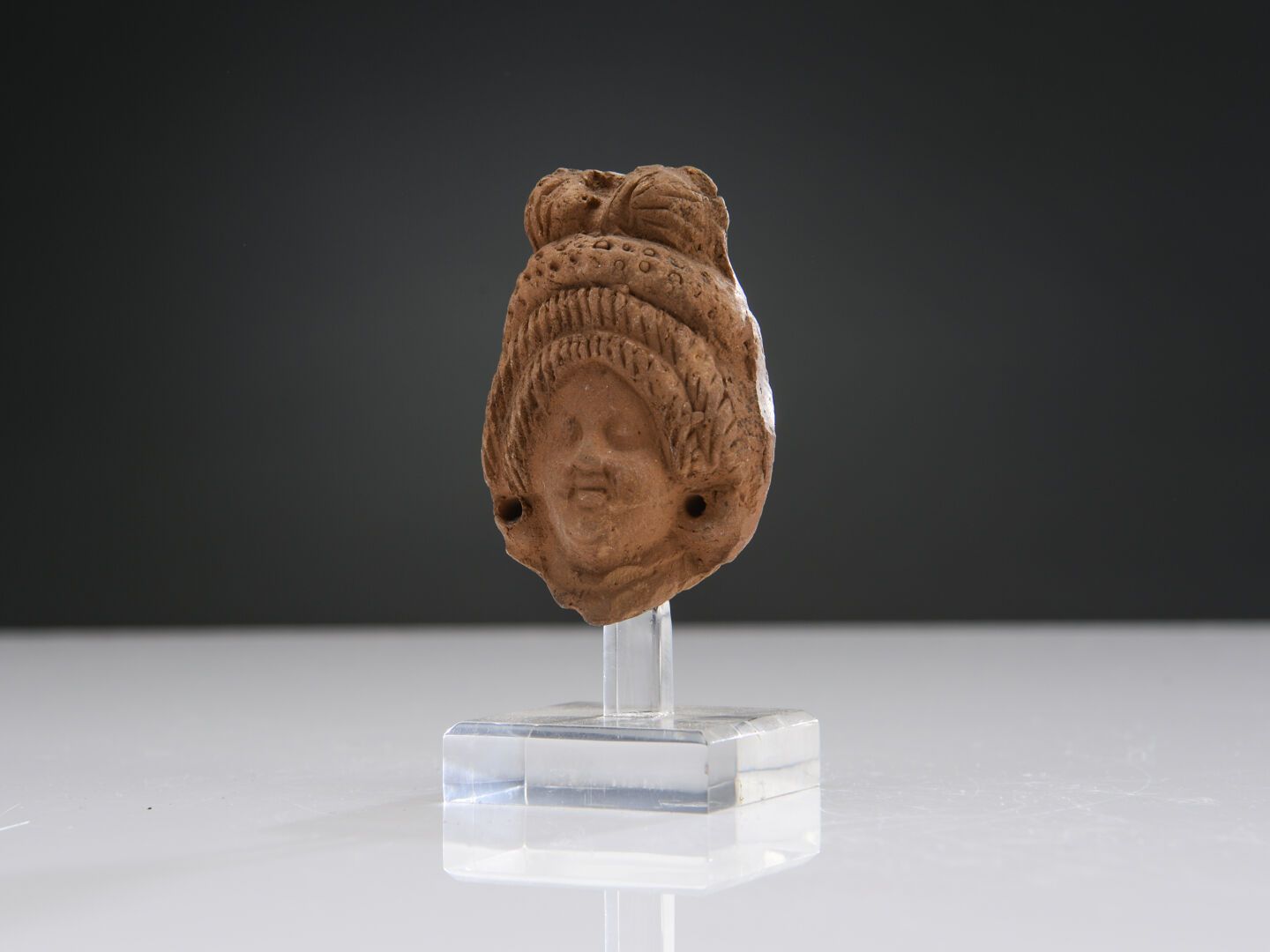 Null 女性头像，有穿孔的耳朵。她的头饰由两排袖子组成，上面有一个厚厚的植物冠。
赭色陶土。
亚历山大城，罗马时期。
H.6.8厘米。
出处：M. B. 收藏&hellip;