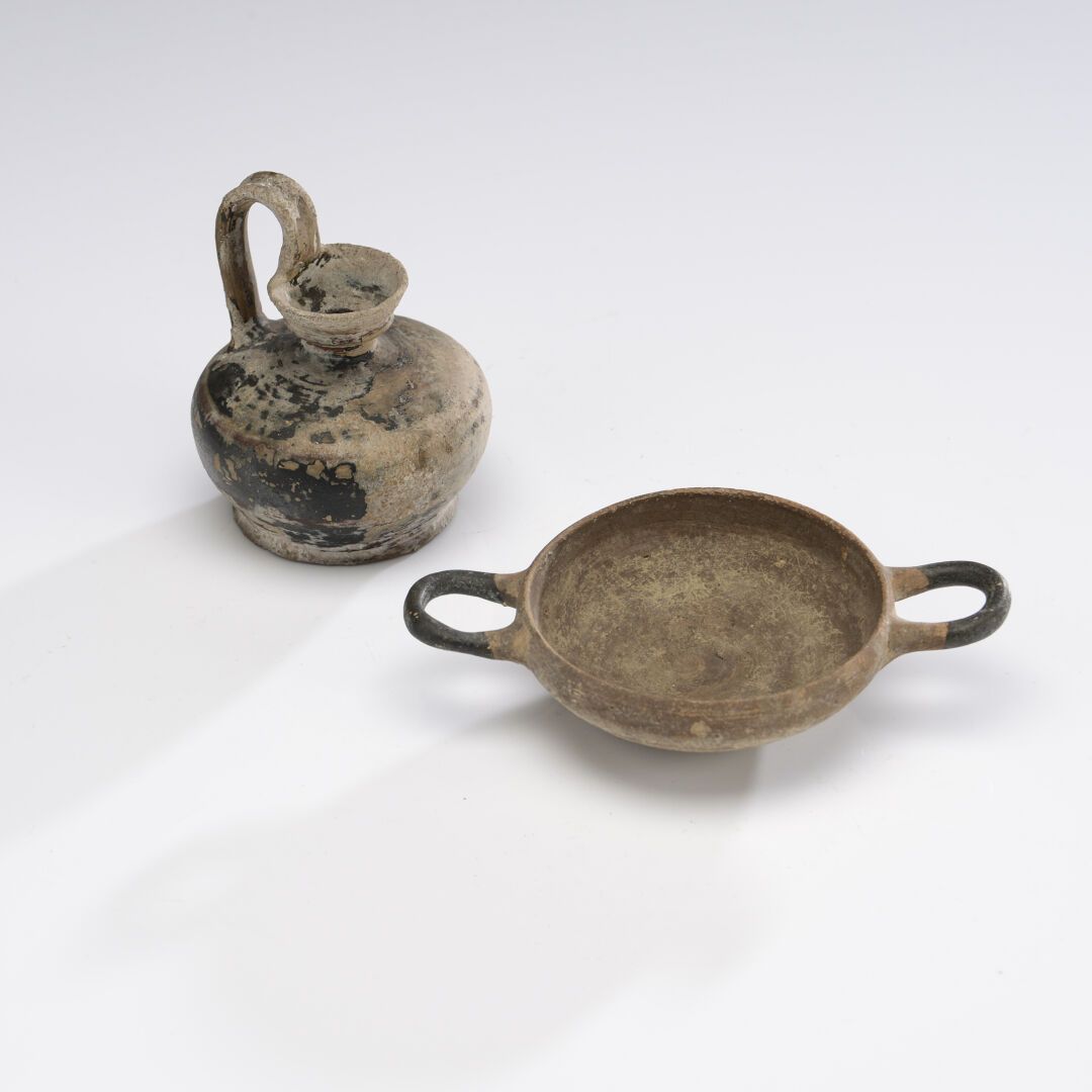 Null 拍品包括一个黑漆的高位双耳柄的Oenochoe和一个横柄碗。
陶器。磨损，石灰石沉积。
大格拉西亚，公元前4世纪。
长：15；高：10.5厘米。
19&hellip;