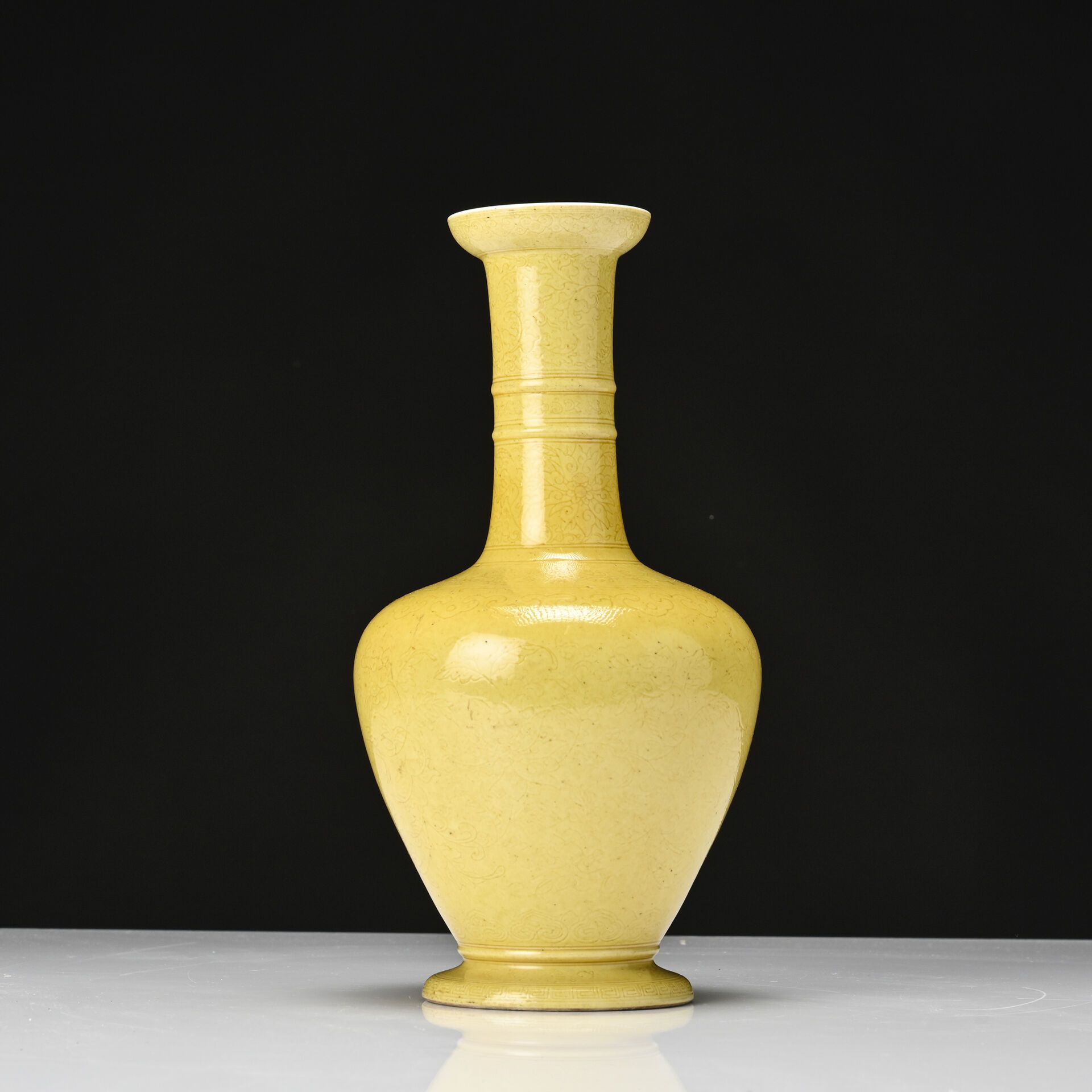 Null 中国，19 世纪、 
黄色单色釉瓷小跟花瓶，长环颈，釉下刻画荷花和如意花环装饰。 
底有雍正癸丑年款。 
高：27 厘米