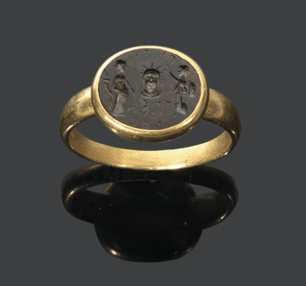 Null 黄金戒指上镶嵌着血碧玉凹版，表现了一个带着光芒四射的皇冠（Helios）的半身像，周围是一个手持玉米棒的女神和另一个正在崇拜的人物。背景上有希腊字母的&hellip;