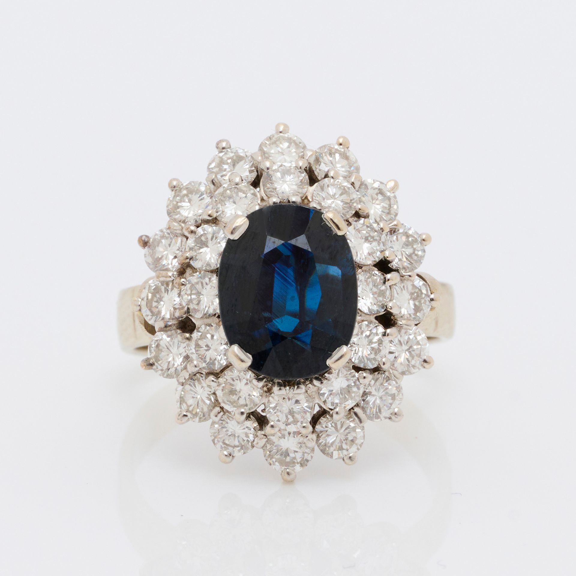 Bague 一枚18K(750/000)白金蓬巴杜戒指，中央是一颗重约1.50克拉的椭圆形蓝宝石（宝石的大约尺寸：9 x 7 x 3毫米），镶嵌在由28颗明亮式&hellip;