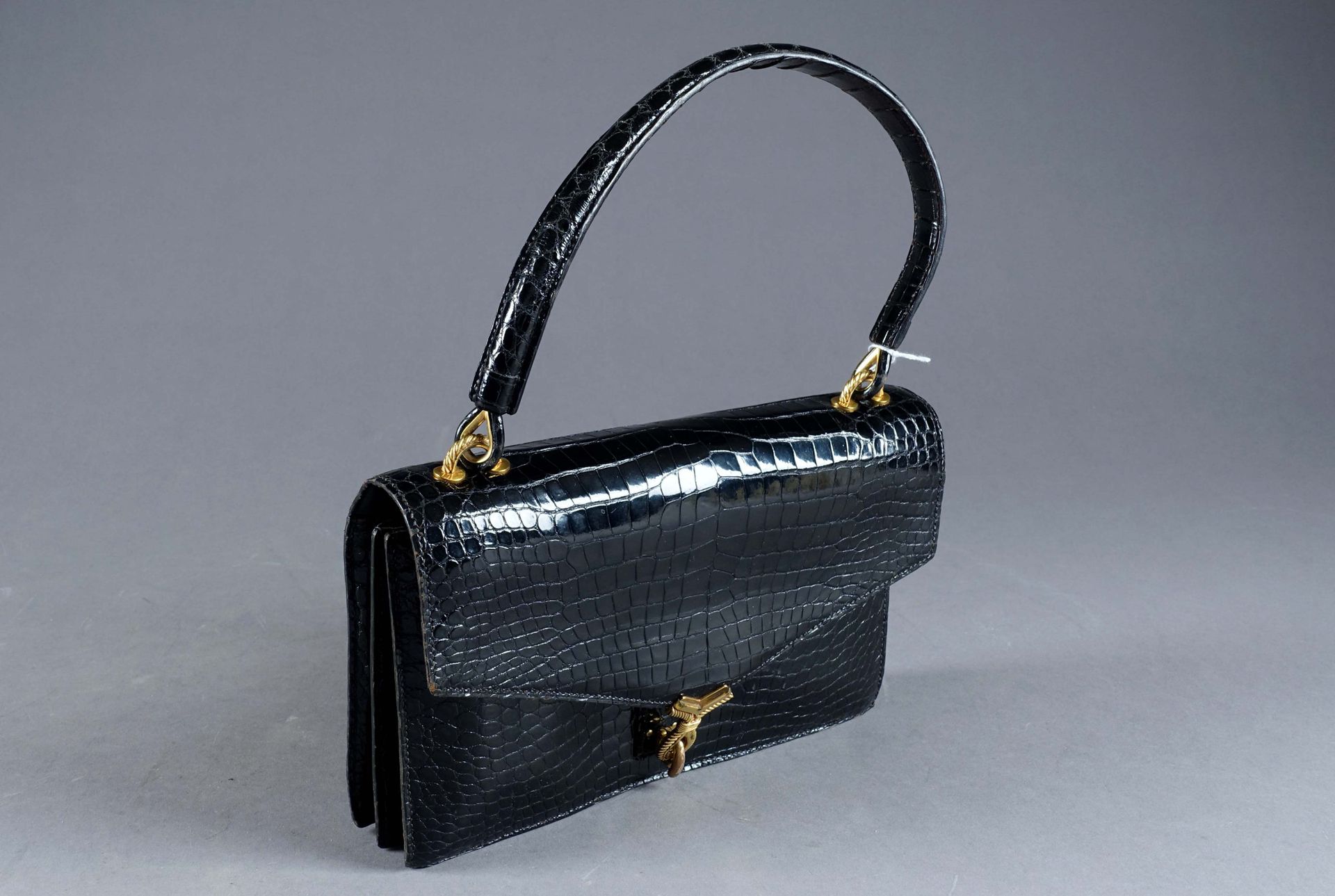 HERMES - PARIS. 来自 "Cordelière "系列的手提包，有两个内部隔层和三个口袋。镀金金属的配件和搭扣。黑色清漆的鳄鱼皮。约1960年。状&hellip;