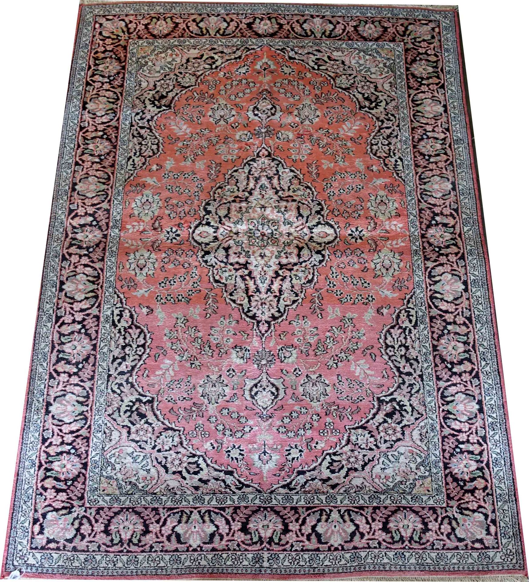 Carpette Ghoum. 背景是洒满鲜花的粉红色，中间是一个椭圆形的奖章。黑色的背景边框。丝绸。尺寸：182 x 125厘米。