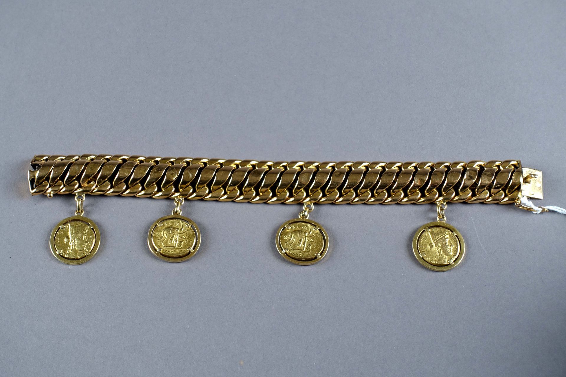 Bracelet Manchette. 点缀着装在吊饰中的古董硬币的复制品。镶嵌在18K黄金中。重量：73.1克。长度：19厘米。