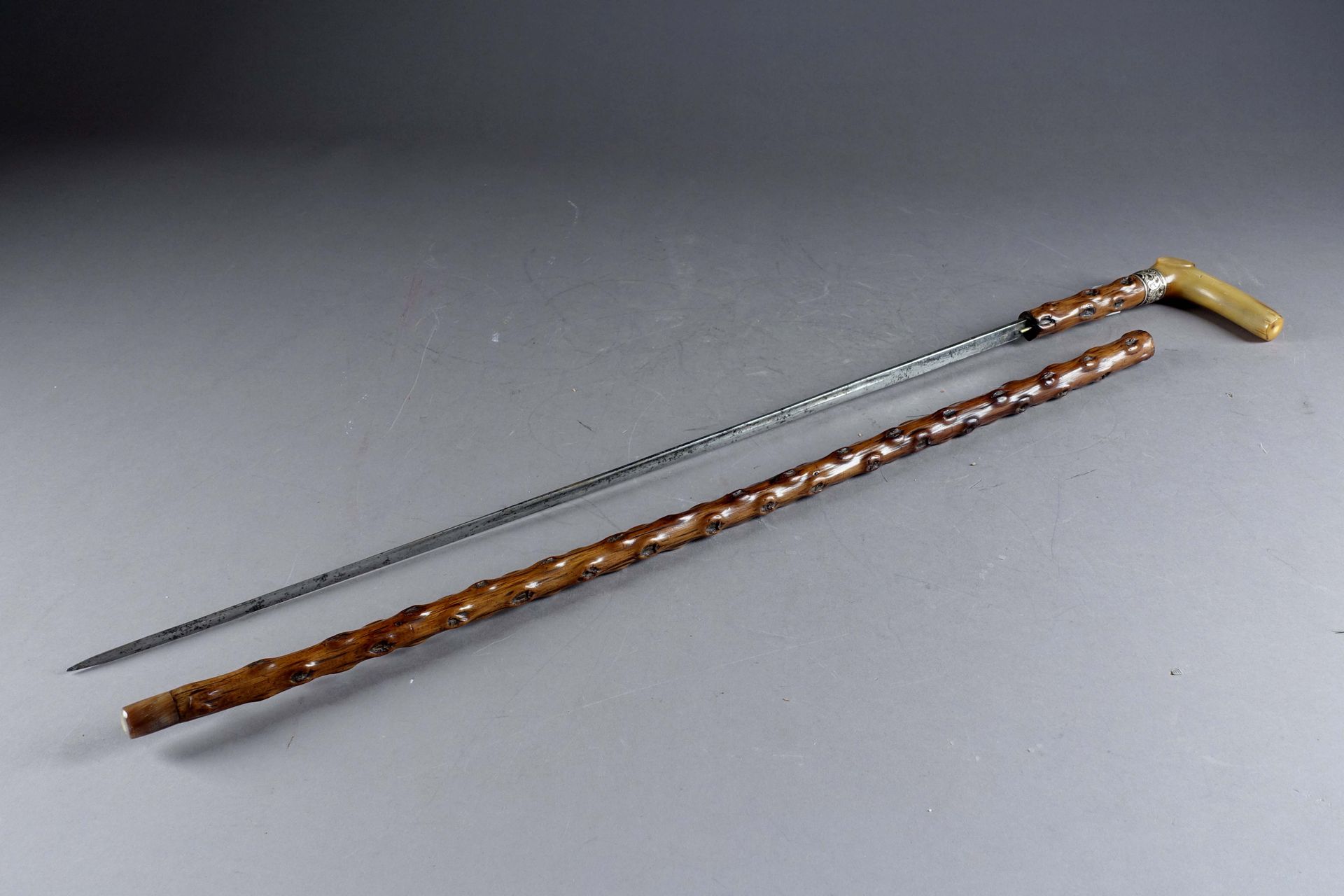 Canne-épée. 沟槽刀片。雕刻的牛角握把，银色套圈。木制刀鞘。十九/二十世纪。长度：90厘米。