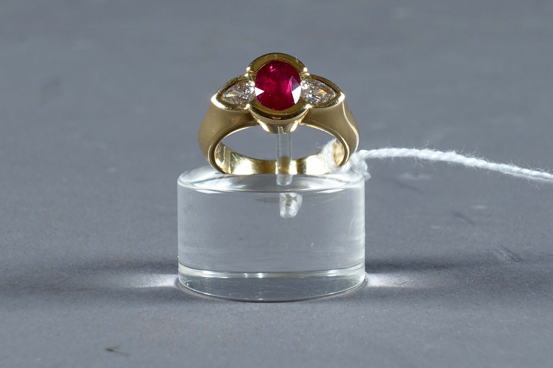 Bague de Dame. 镶嵌着一颗椭圆形切割的红宝石（约1克拉30），两侧是两颗梨形切割的钻石（约0克拉45）。镶嵌在18克拉的黄金中。重量：10.3克。&hellip;