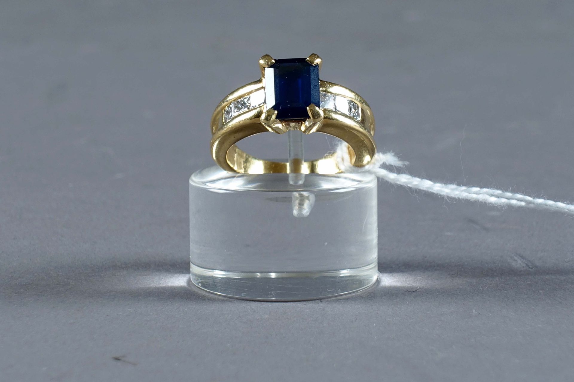 Bague de Dame. 镶嵌着一颗祖母绿切割的蓝宝石（约2克拉35），两侧是六颗公主切割的钻石（约0克拉70）。镶嵌在18K黄金中。重量：10.1克。大小&hellip;