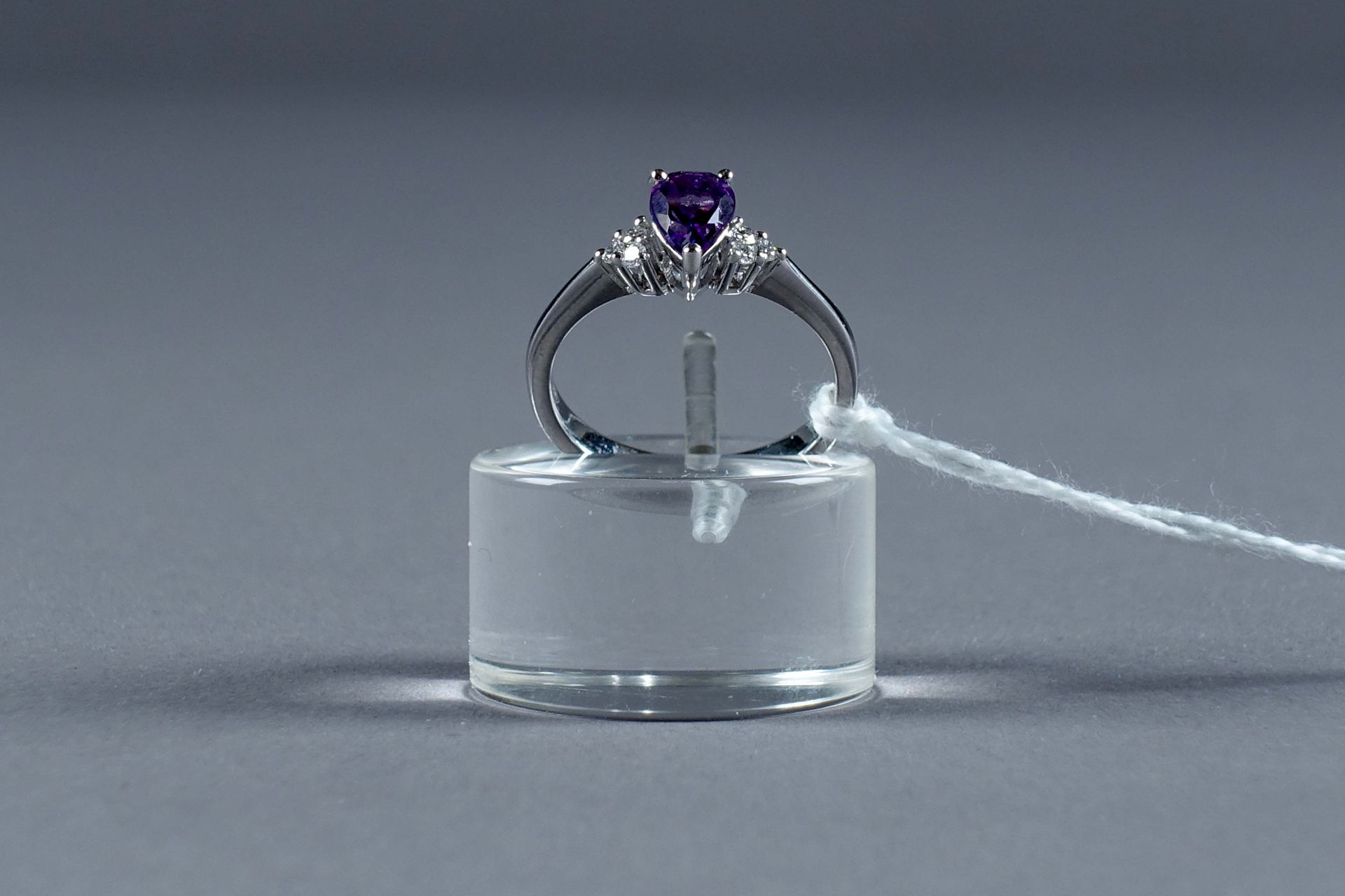 Bague de Dame. 镶有一颗梨形切割紫水晶（约0克拉65），两侧是六颗明亮式切割钻石（约0克拉10）。镶嵌在18K白金中。重量：3.3克。大小：54。