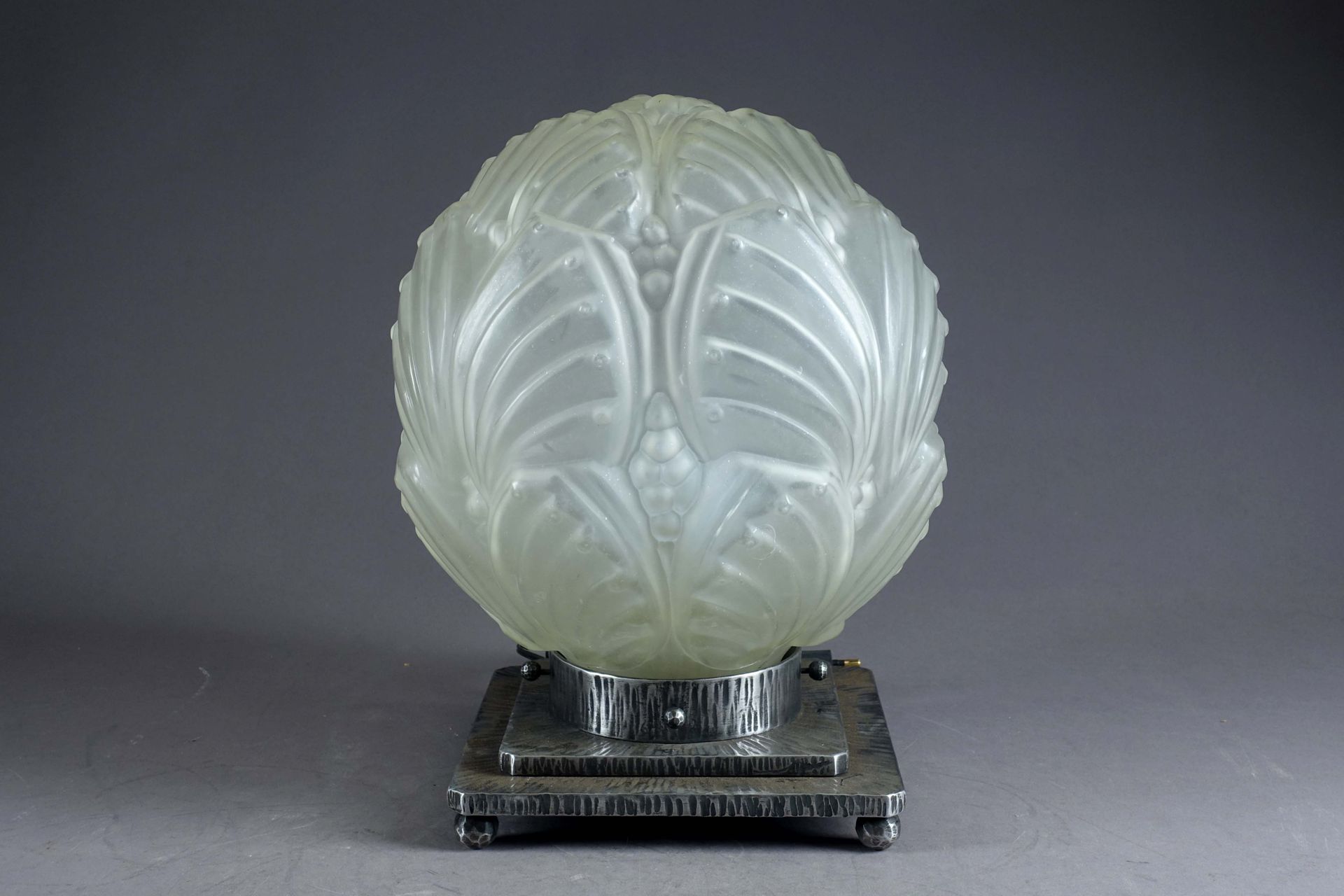 Grande Lampe de table Art Déco. 一个模制和磨砂玻璃的球体，带有风格化的蝴蝶翅膀，放在一个有四个球脚的锤锻铁的底座上。高度：33厘&hellip;