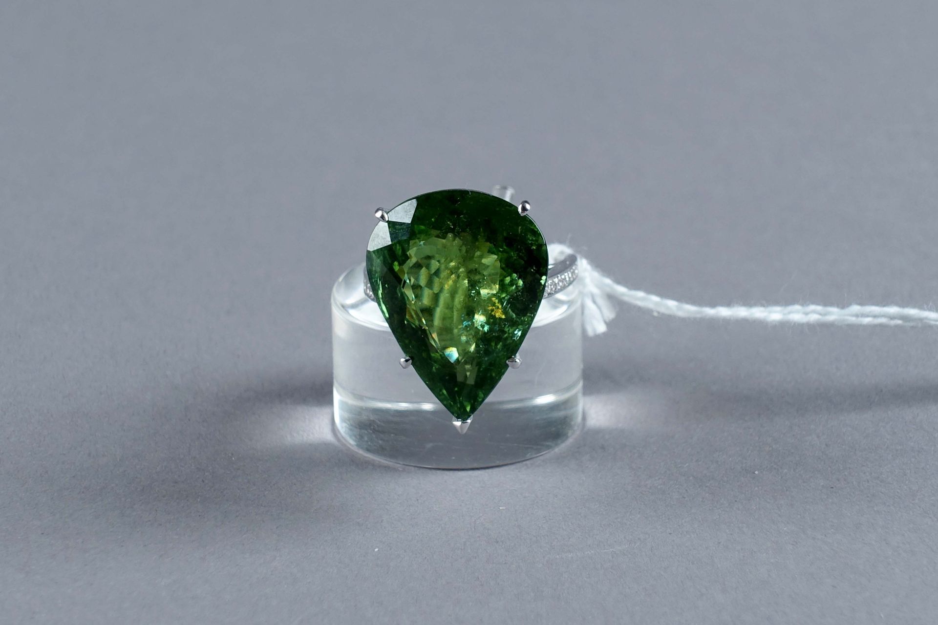 Bague de Dame. 镶嵌有一颗大型梨形切割帕拉巴碧玺（约24克拉40），两侧是20颗明亮式切割钻石（约0克拉20）。镶嵌在18K白金中。重量：10.4&hellip;