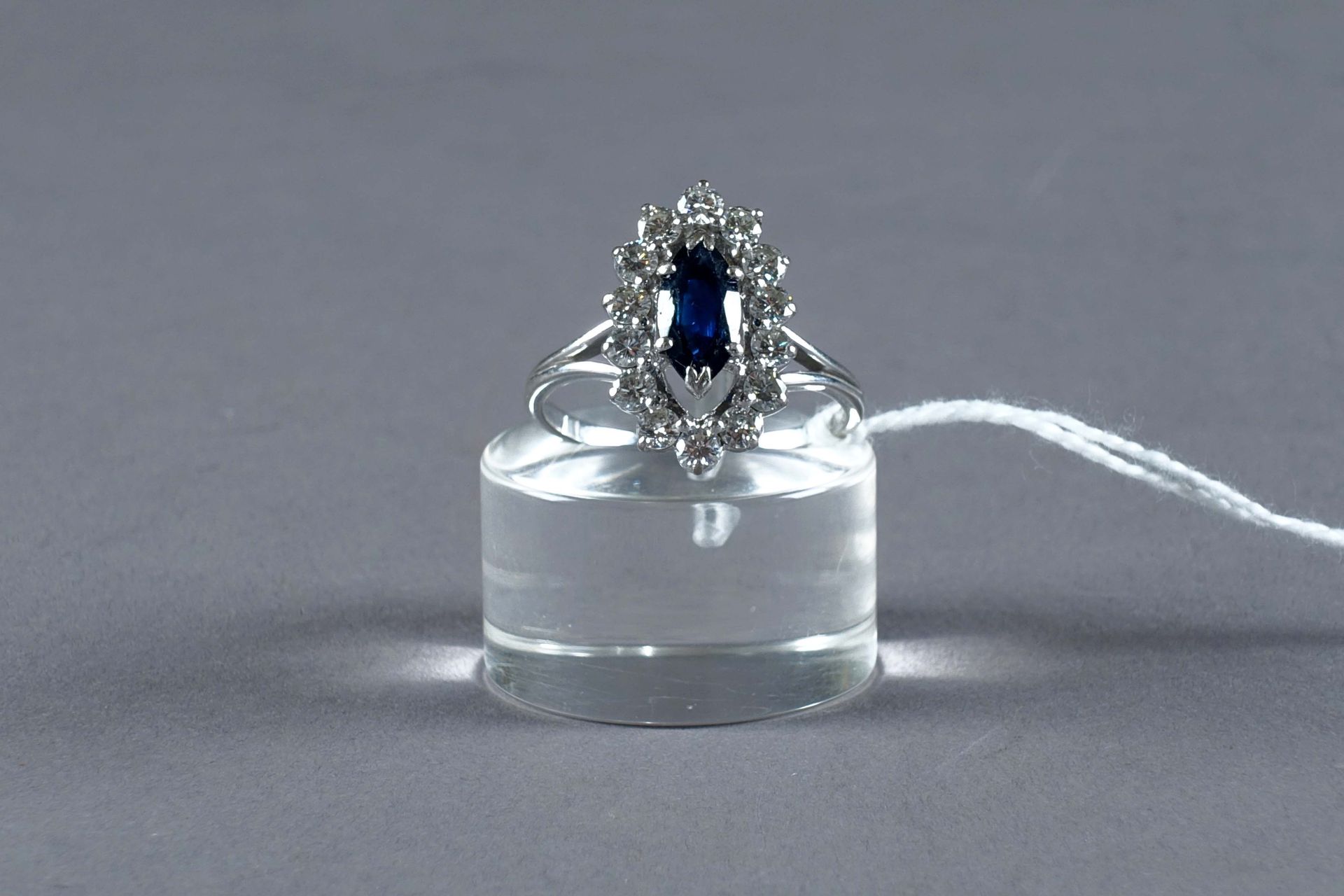 Bague de Dame. 镶嵌着一颗侯爵式切割的蓝宝石（约0克拉90），并镶有14颗明亮式切割钻石（约0克拉70）。镶嵌在18K白金中。重量：4.3克。大小&hellip;