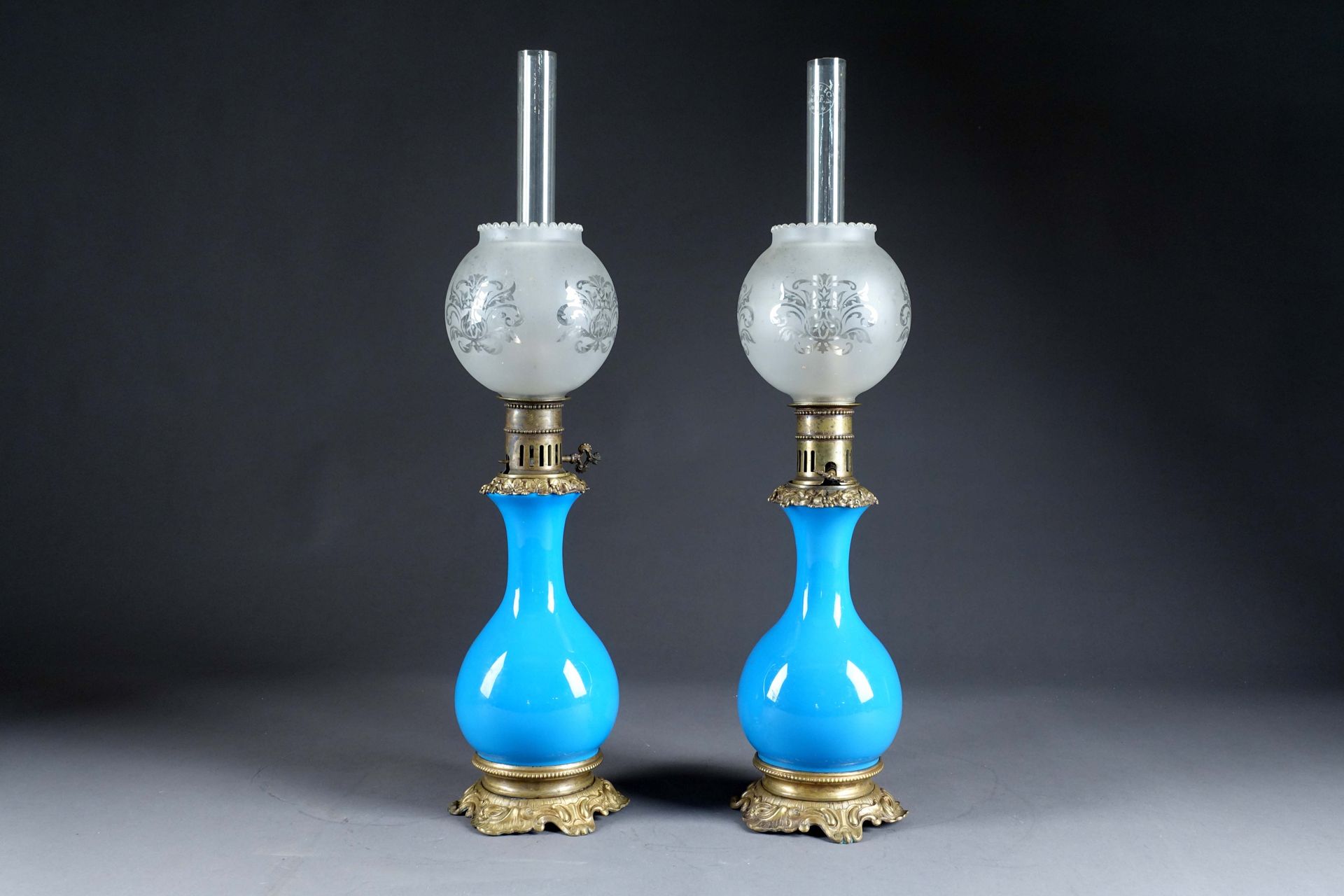 Paire de lampes Carcel. 一个天蓝色的乳白色海棠形水箱。安装和脚上有铜制的贝壳。拿破仑三世时期。有管子和玻璃球。高度：60厘米。