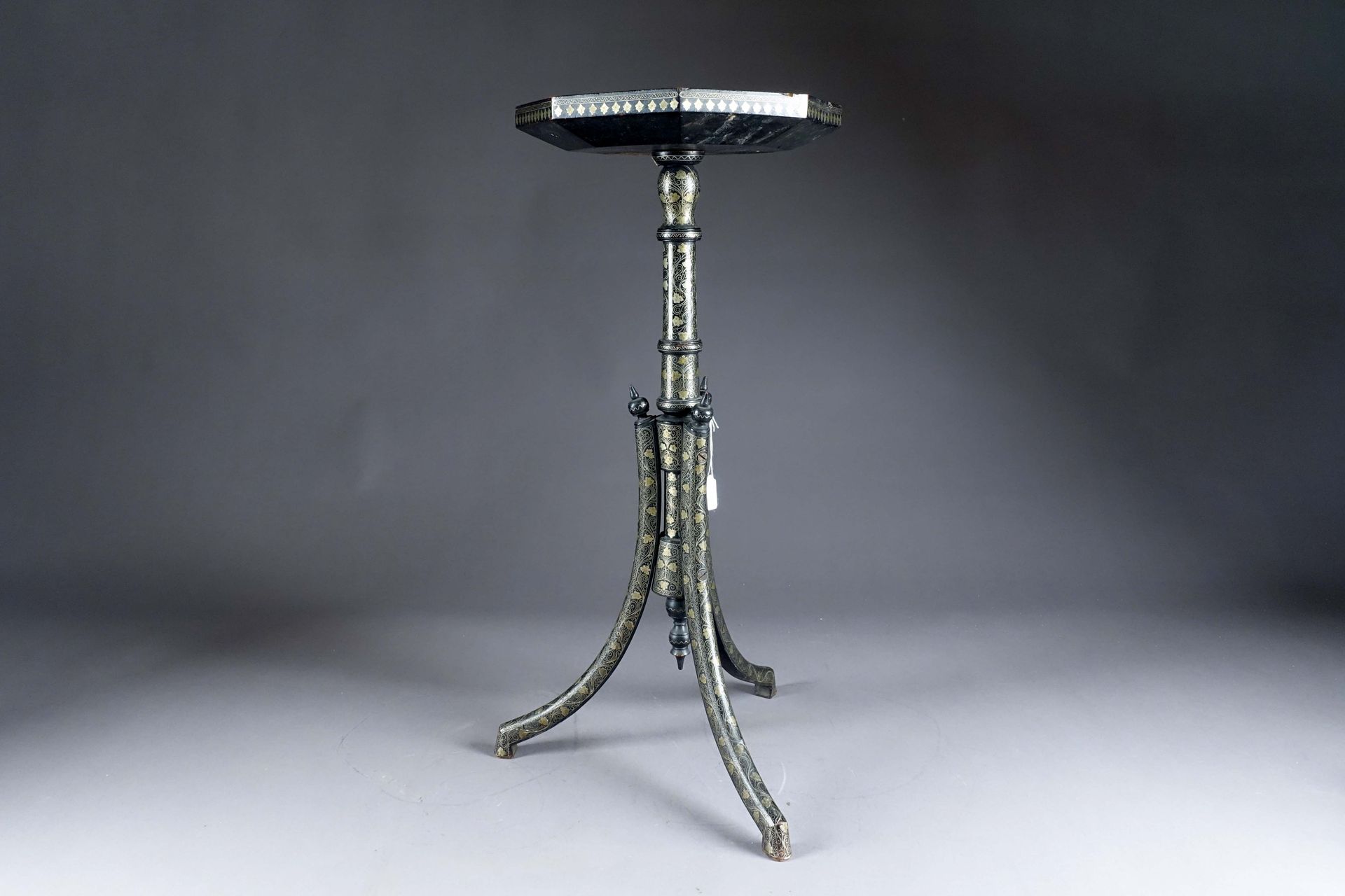 Vortik Potikian. 一个罕见的奥托曼式边桌，有一个八角形的桌面，放在一个由三个拱形腿延伸的轴上。黑色抛光的木头上镶嵌着细丝和银色的图案，形成了叶状&hellip;
