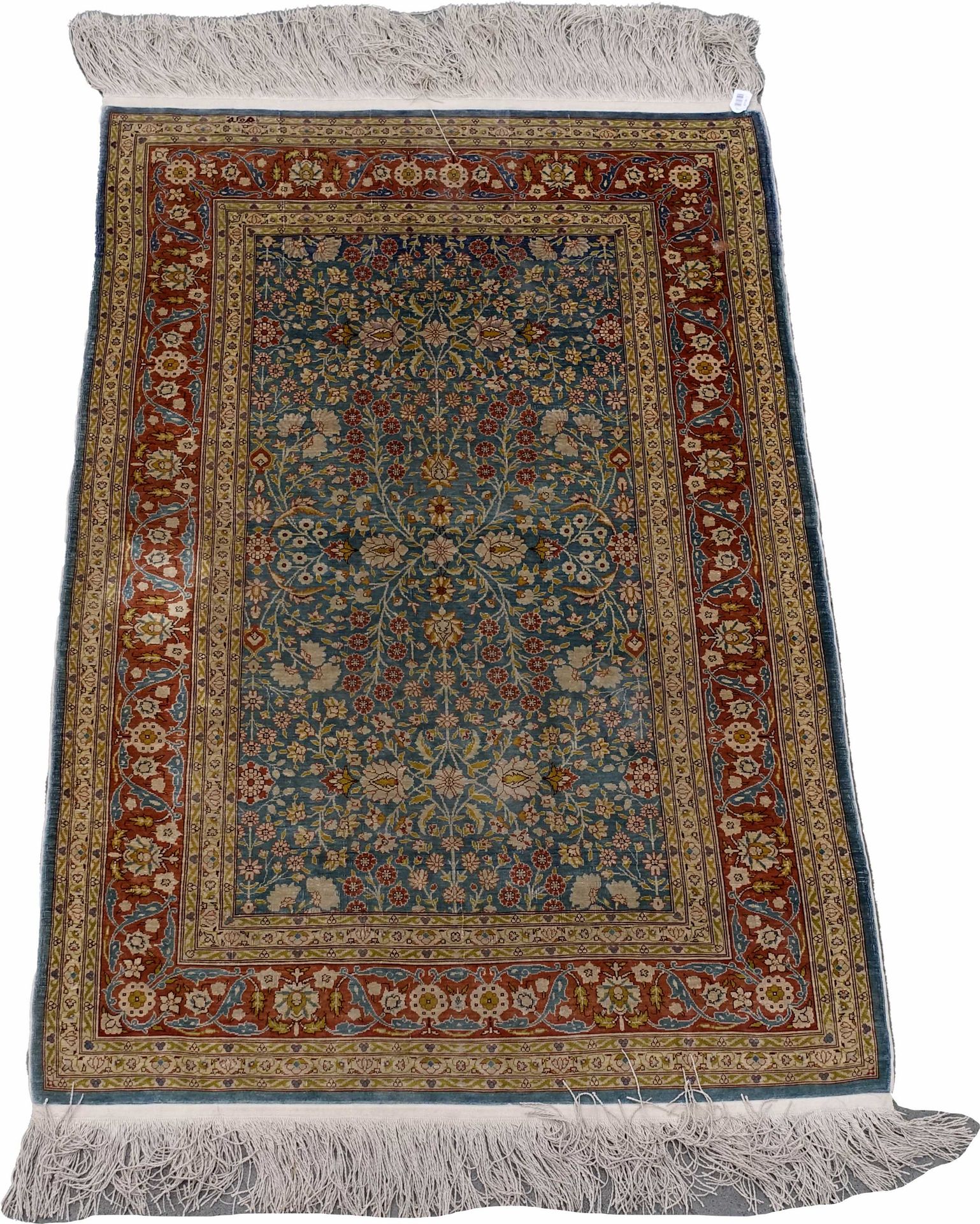 Carpette Héréké. The background is blue-green with small polychrome flowers. Red&hellip;