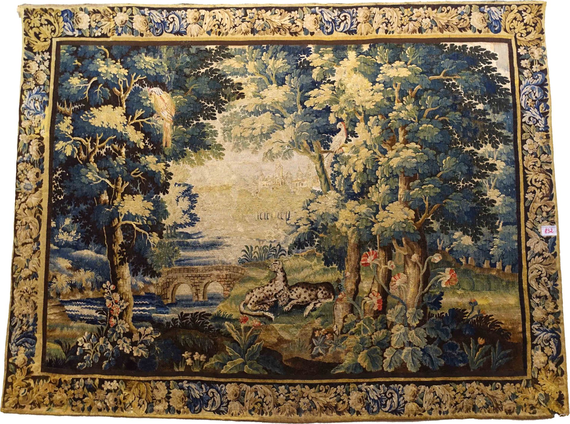 Tapisserie d’Audenarde. 它显示了一对豹子在一个有树的花园里，一只鹦鹉在河上飞行，远处是一个村庄。花卉边框。18/19世纪的作品。状况良好&hellip;