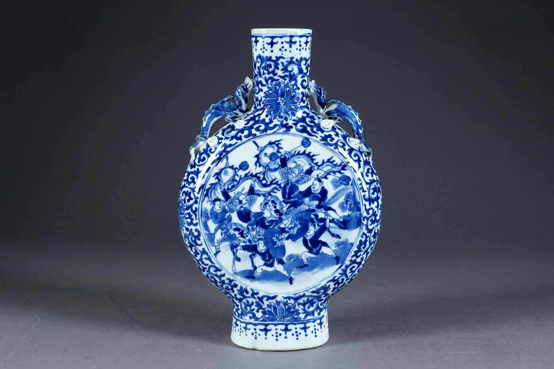 Chine - Période Qing. Moonflask "花瓶。颈部两侧有两条龙，两侧饰有骑士和战士的图案，以叶子为边框。瓷器上有白色/蓝色的珐琅。高度&hellip;
