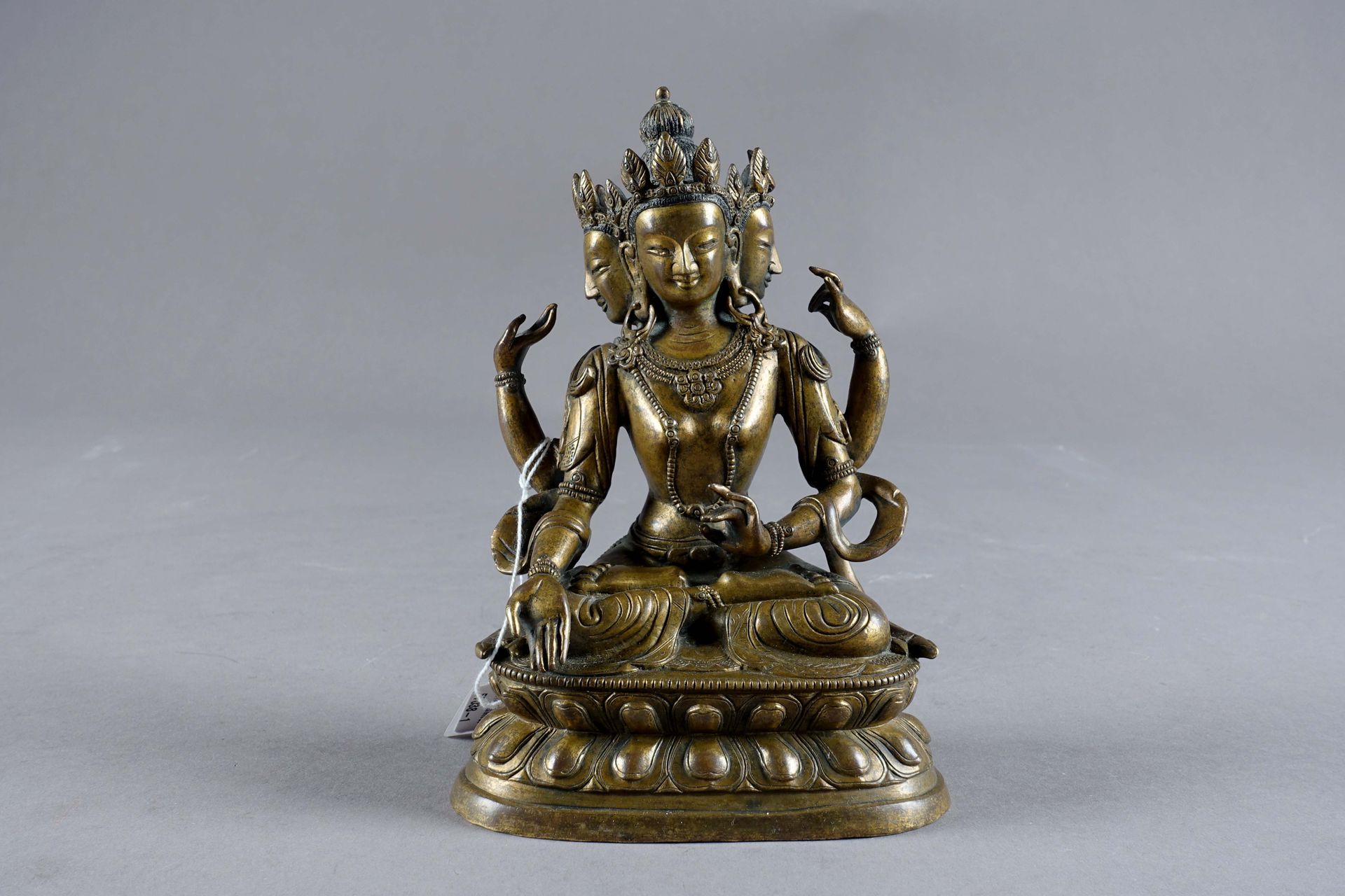 Avalokiteshvara assise en padmasana. 描绘了三个头和四条胳膊，躯干上装饰着项链。她站在一个有两个双排莲花瓣的底座上。青铜器。&hellip;