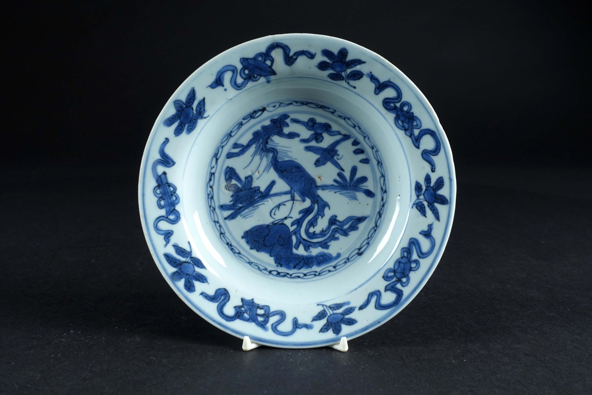 Chine - Epoque Ming, de la période Wanli. 一个小圆瓷盘，白色/蓝色珐琅，上面有一只岩石上的天堂鸟。直径：19厘米。状态&hellip;