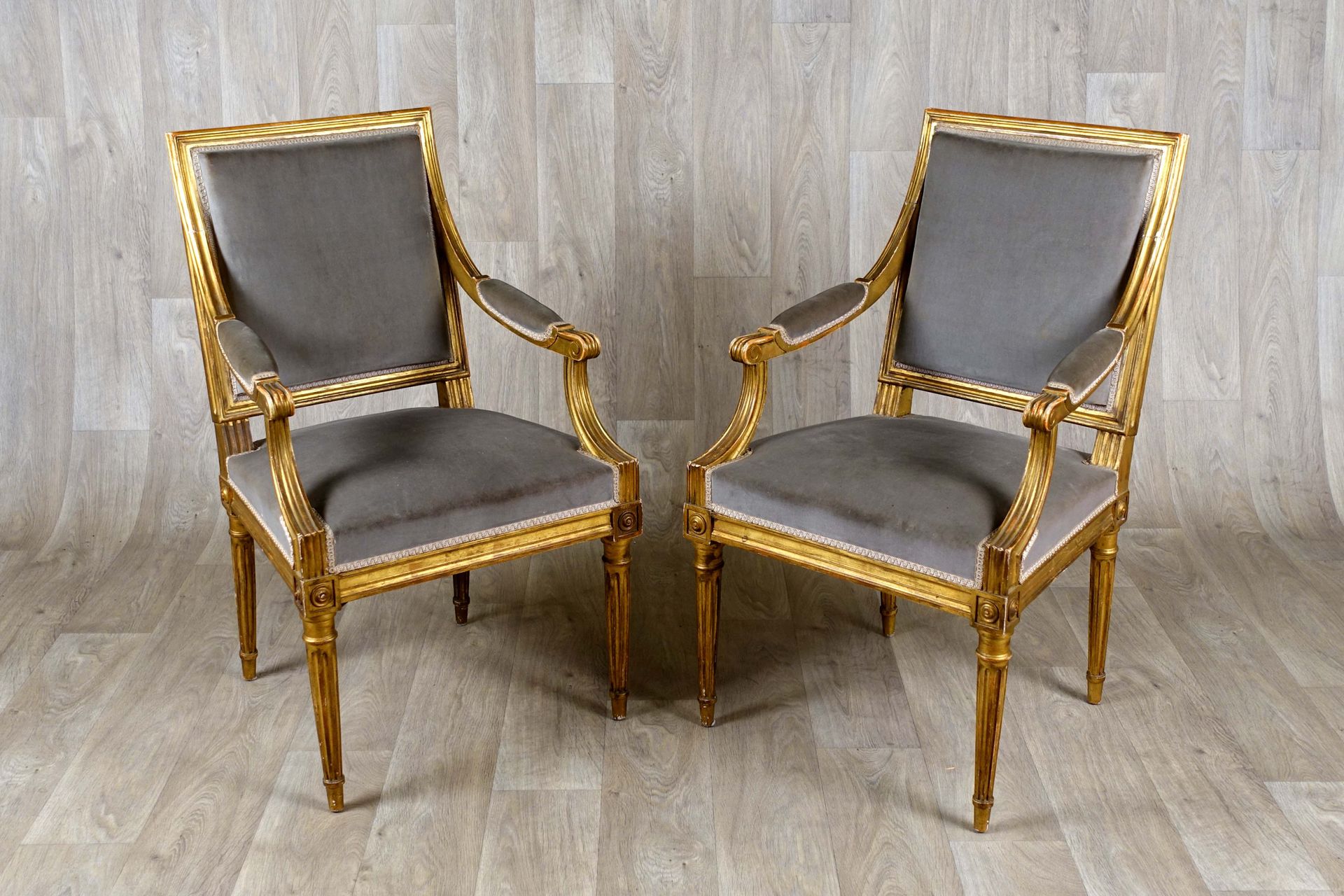 Paire de fauteuils de style Louis XVI. 直线倾斜的背部。扶手上装饰有袖口。带凹槽的锥形腿。镀金的木材。20世纪的作品。