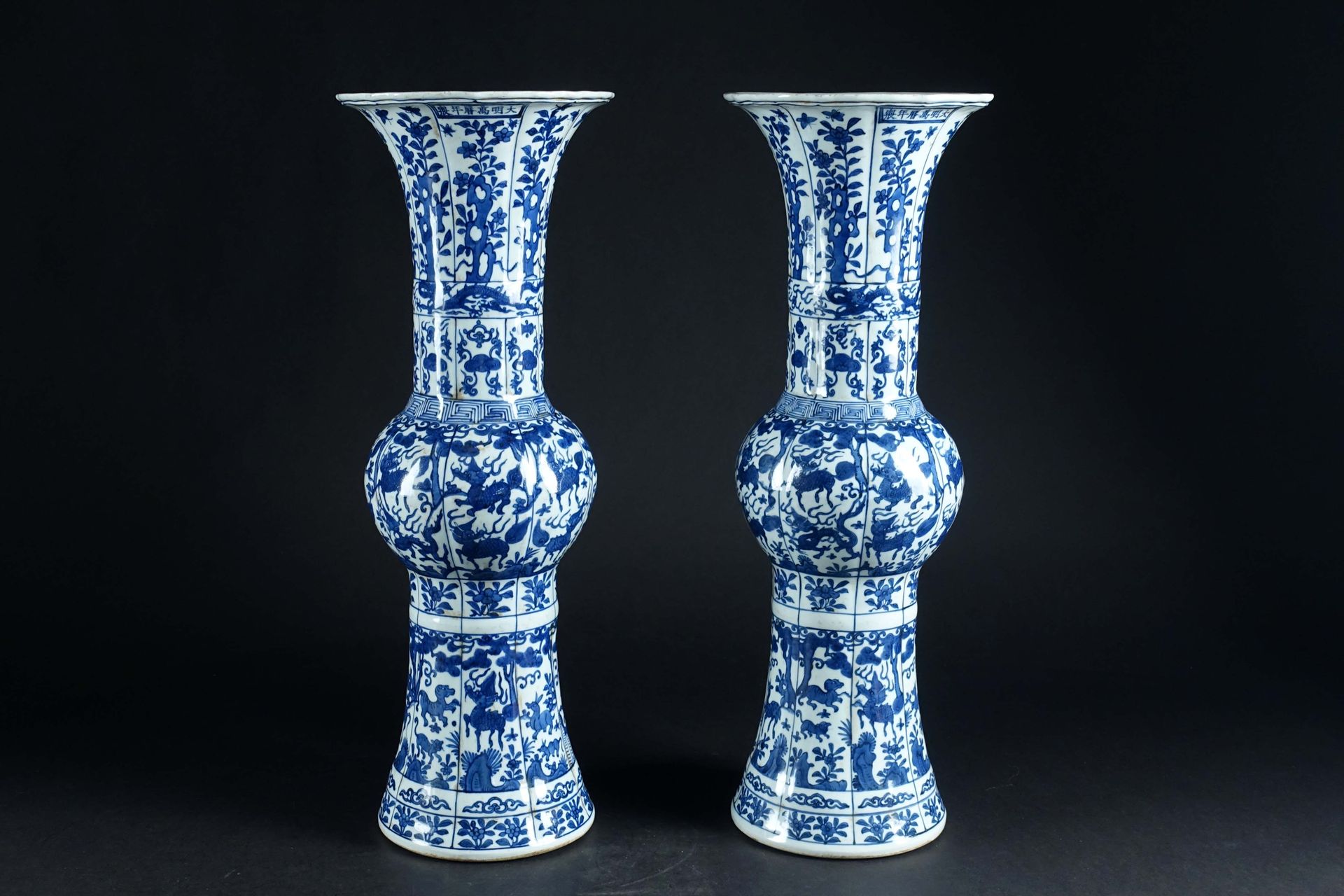 Paire de grands vases “Gu“. 中国瓷器，白色/蓝色珐琅彩，饰有神兽、吉祥物、岩石、花灌木和灵芝。颈部有六个字的万历伪经印记。高度：62&hellip;