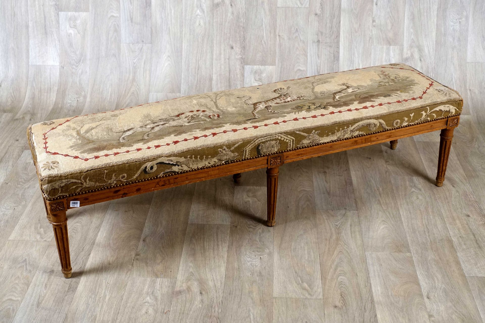 Banquette. 模制的支架和带凹槽的锥形腿。榉木软垫，带有豹纹狩猎装饰。路易十六时期的作品。尺寸：42 x 162 x 41厘米。