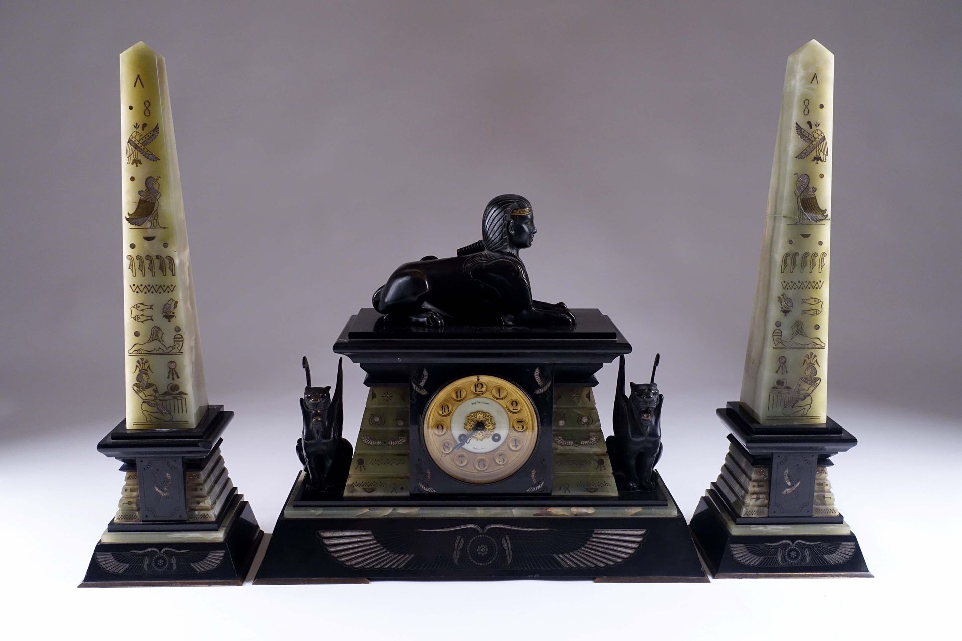 Garniture de cheminée. 19世纪下半叶从埃及返回的风格。由一个时钟和一对方尖碑组成。这座钟是由一座以狮身人面像为顶的神庙形成的。表盘上有布&hellip;
