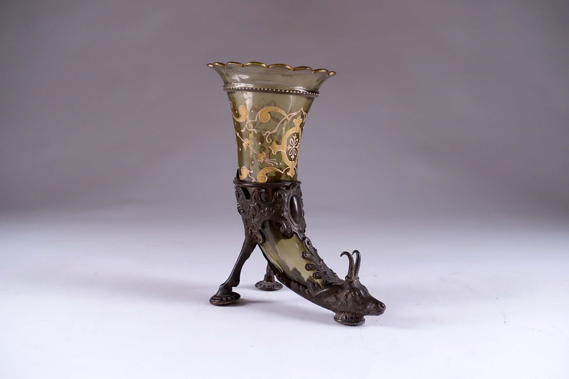 Vase rython. 带珐琅彩玻璃角。由一个带有麂皮头和母鹿蹄足的三角架承载。青铜器。19世纪下半叶。高度：24厘米。状态 : 无事故。