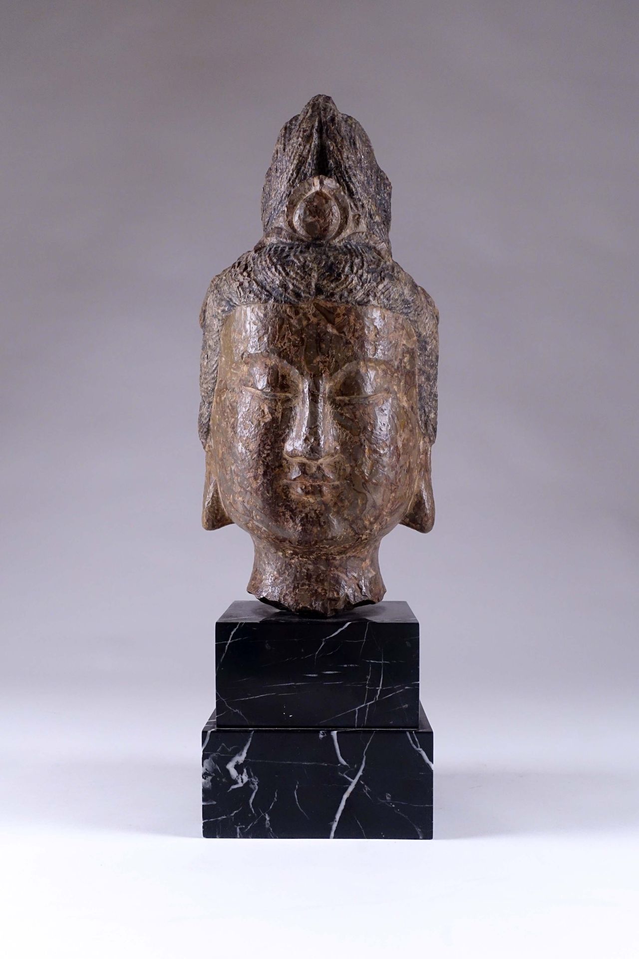 CHINE. Head of Bodhisattva with a bun. Carved stone. Height : 35 cm. On a marble&hellip;