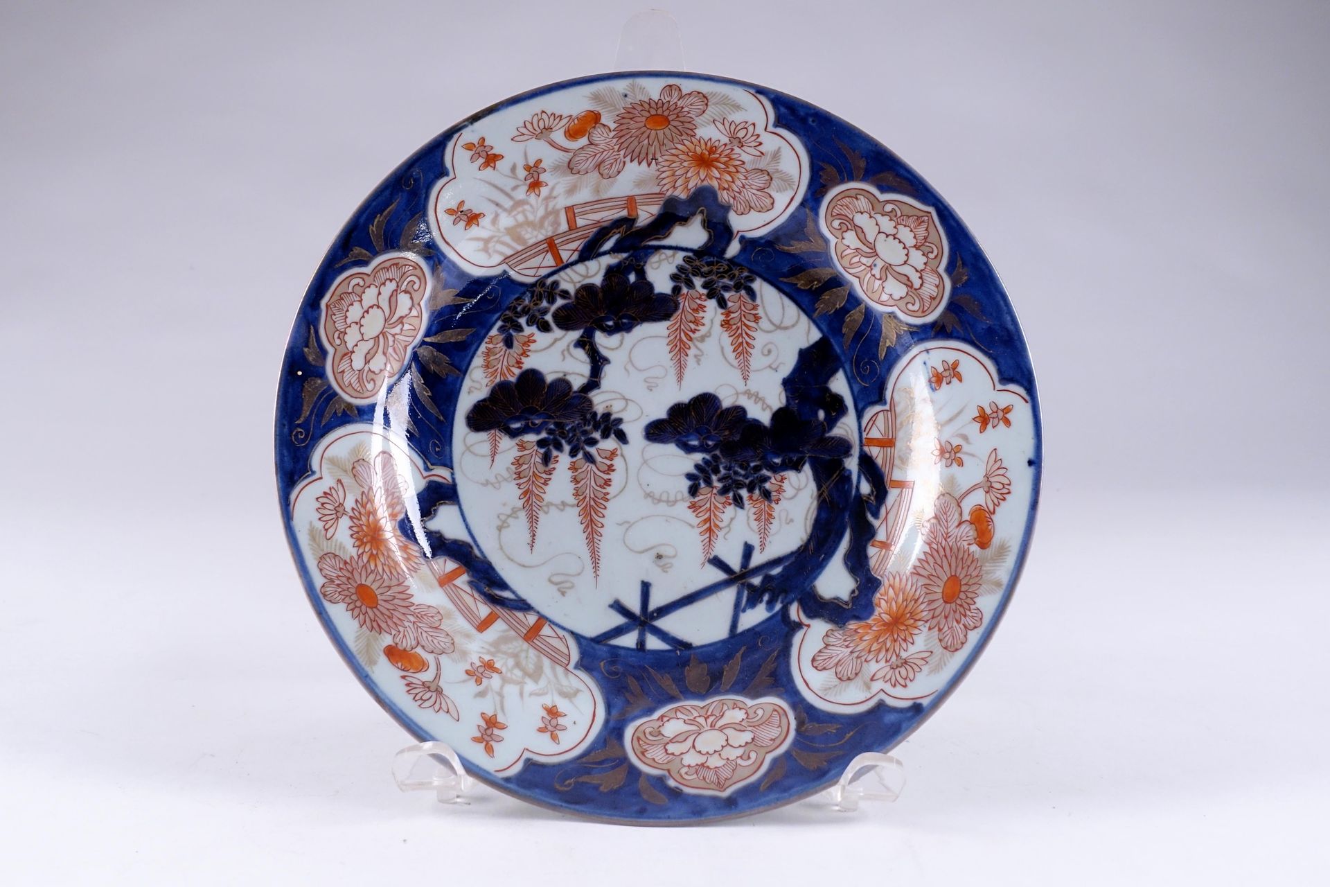 Japon. De la période Edo. 一个圆瓷盘，带有伊万里装饰，中间是一朵盛开的紫藤，翅膀上有六个蓝色背景的花纹图案。直径：29厘米。状态：无事&hellip;