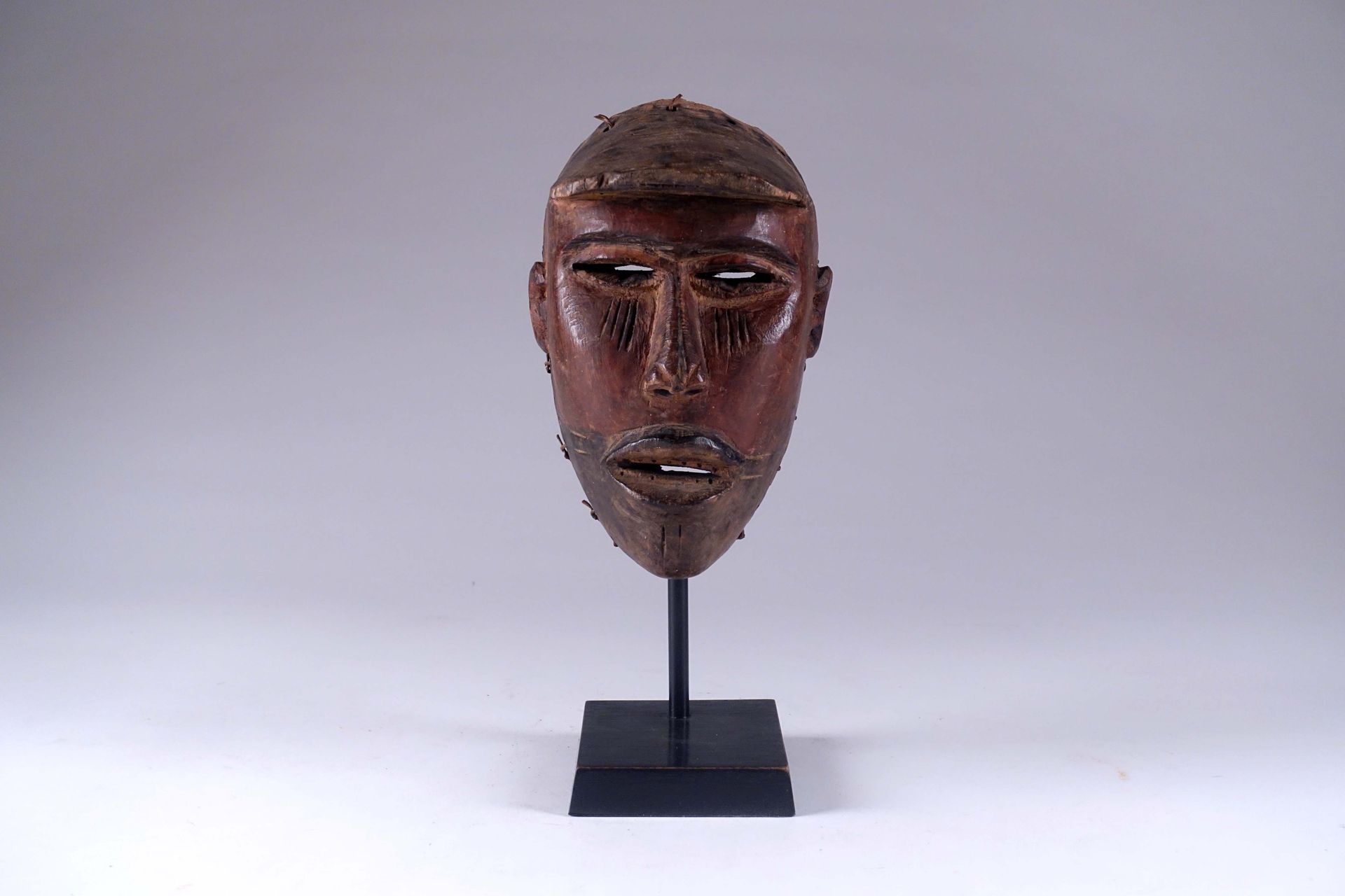 Masque Bas Congo. 描绘了一个脸上有疤痕、戴着面罩的人。雕刻的木头。高度：22厘米。在一个基地上。