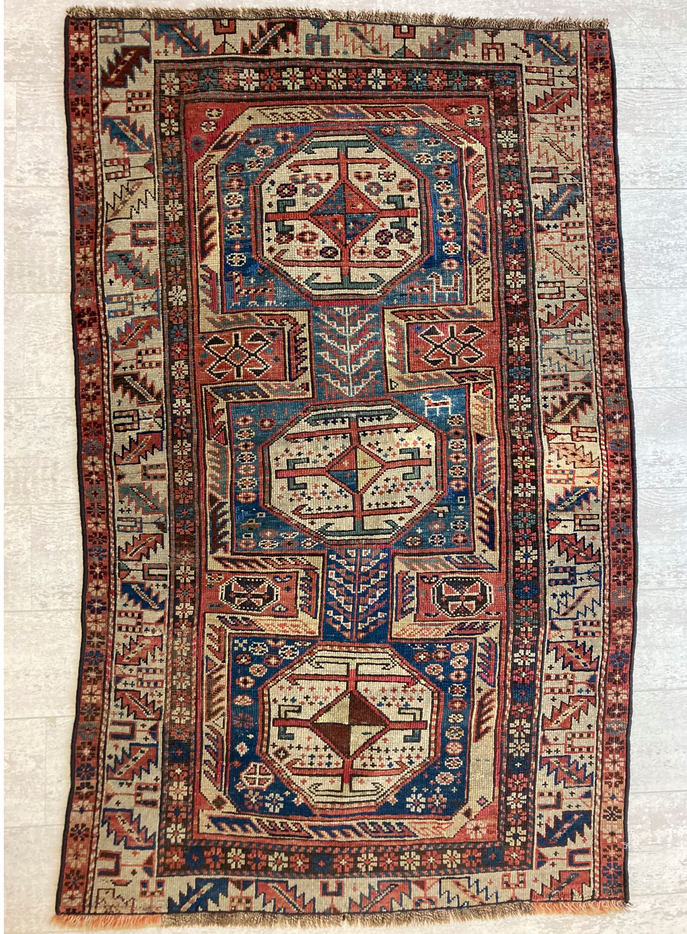 Null 哈萨克羊毛地毯，在蓝色背景上装饰有三个八角形奖章，宽边有几何图案。100 x 160厘米。(穿着)
