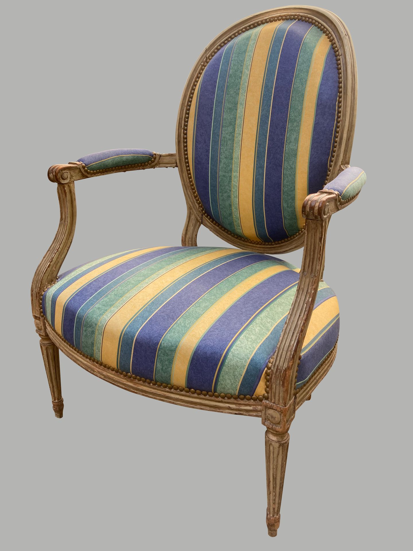 Null 一把奶油色漆木卡布利奥扶手椅，有一个奖章式的靠背，有凹槽的锥形腿，用蓝色、绿色和黄色的条纹织物装饰。路易十六的风格。高97厘米，宽85厘米，深66厘米&hellip;