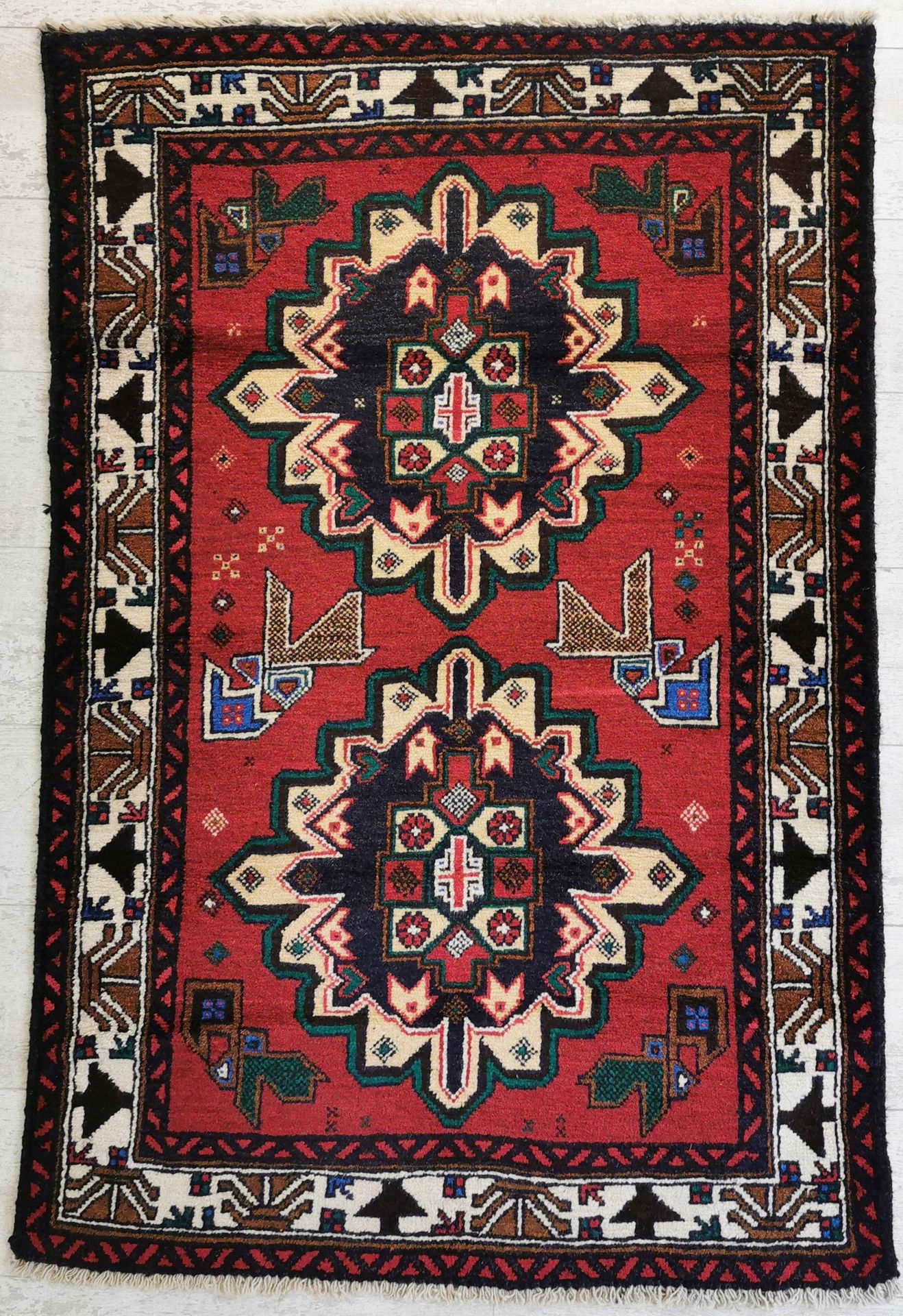 Null 伊朗。羊毛巴鲁什地毯，在红底上装饰有两个蓝色奖章，上面有几何图案和风格化的花朵。86 x 133厘米。