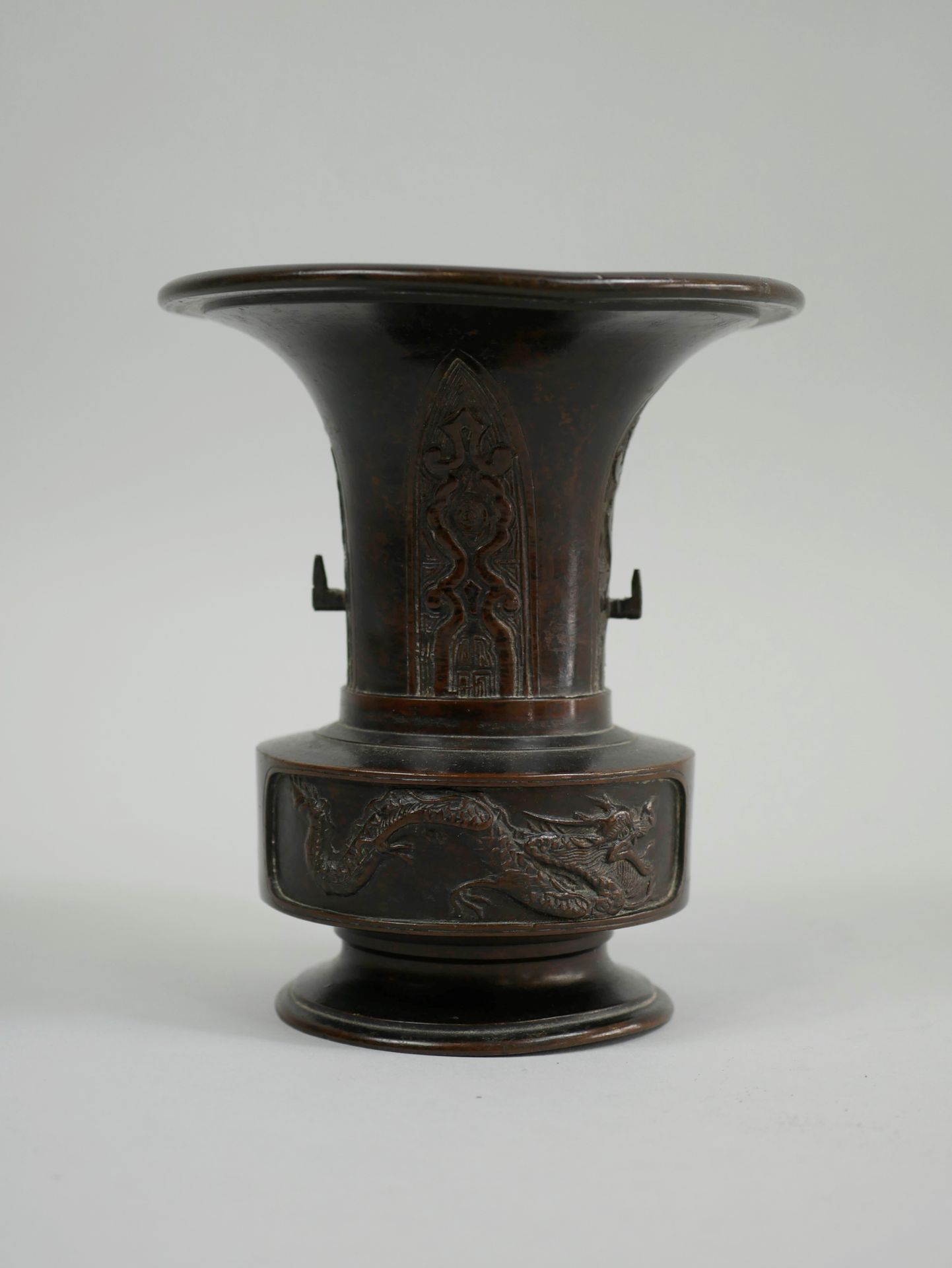 Null 日本。19世纪。棕色铜制的小Usubata花瓶，上面有龙和凤的装饰。高耸的颈部装饰着风格化的蝉鸣声。高14厘米。(脚部和开口处有轻微变形)