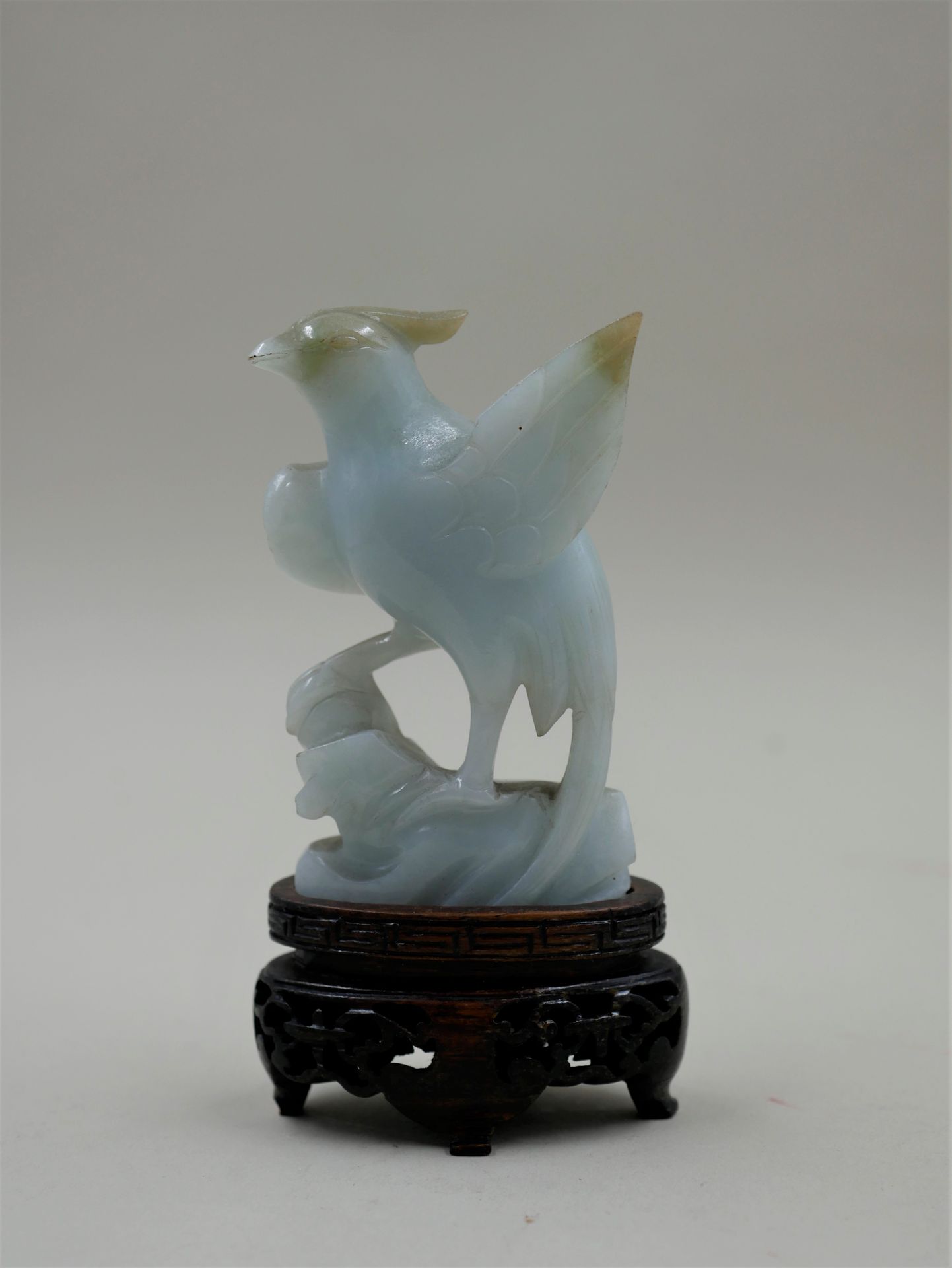 Null Jadeite phoenix on a carved wooden base. Height 8cm.