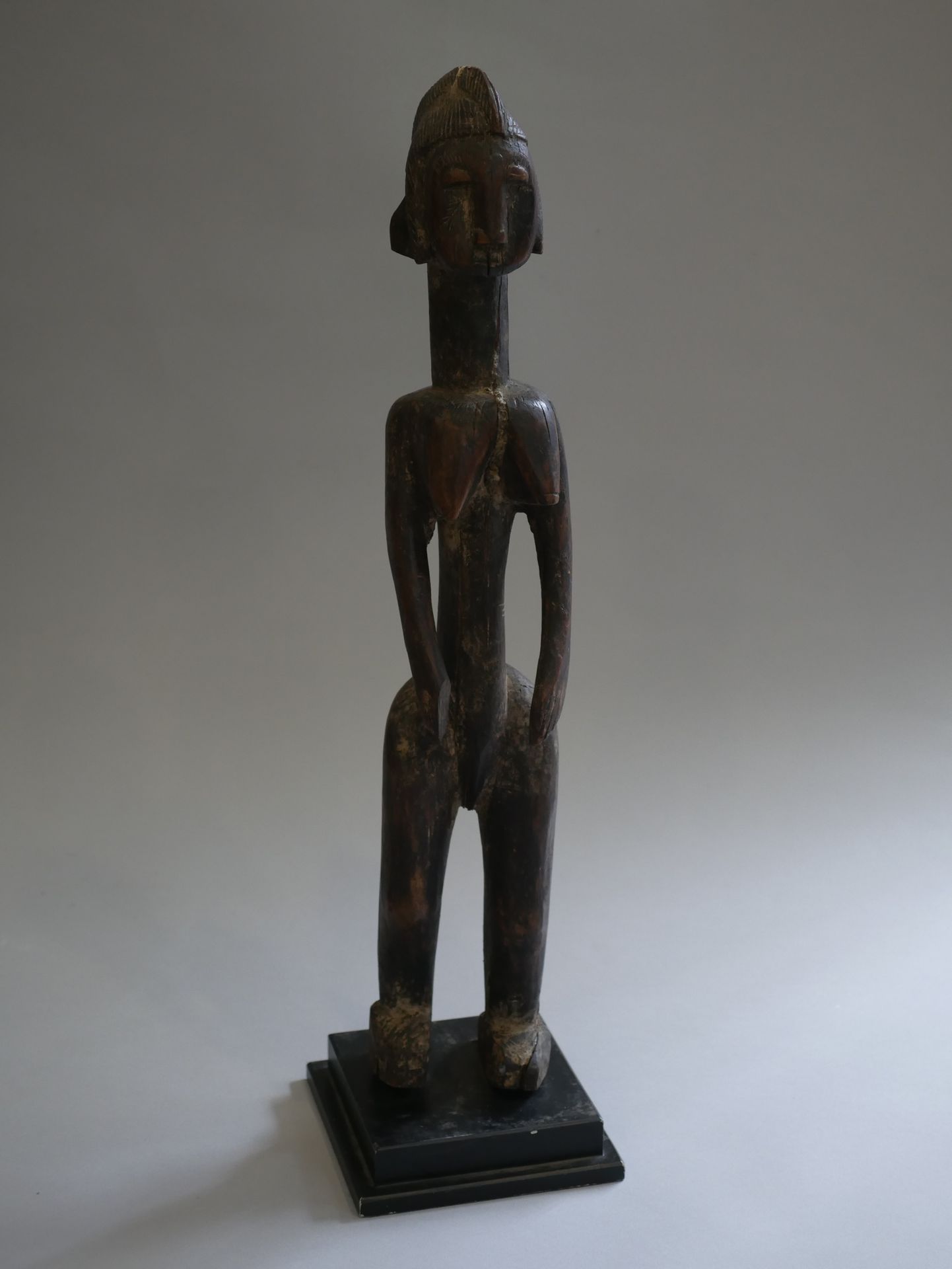Null 马里，BAMBARA。代表一个站立的女性形象的木制雕像，手臂沿着躯干，有造型的手，脸部被高高的头饰所覆盖，有徽章。

 高度：52厘米。高度：52厘米&hellip;