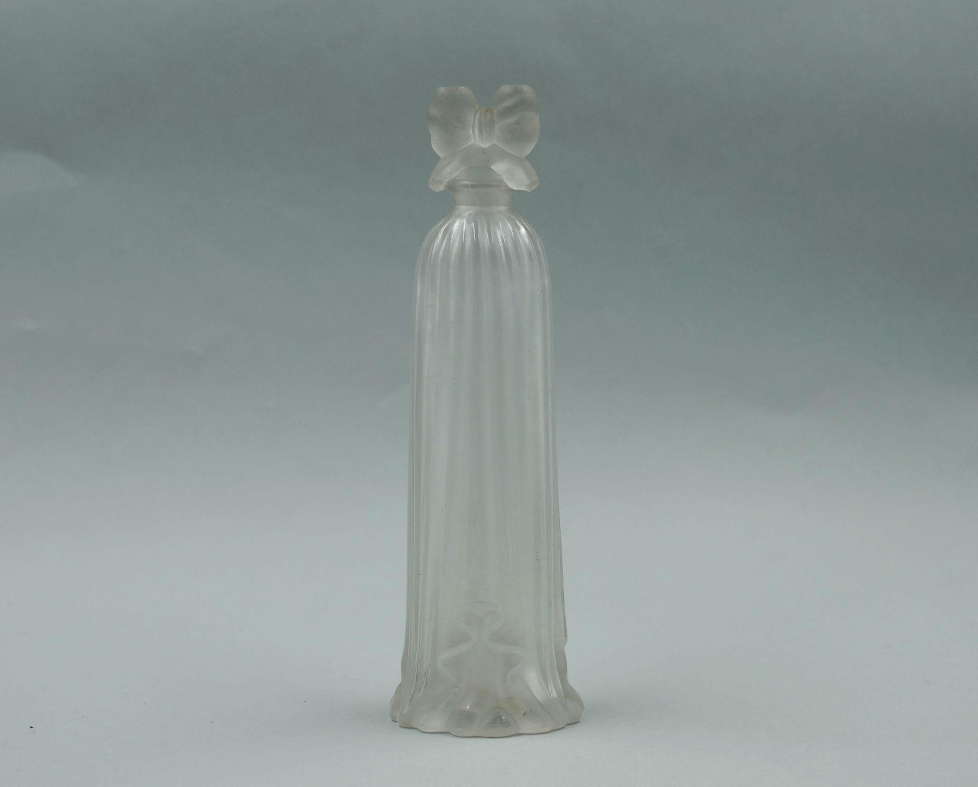 Null 压制成型的玻璃香水瓶 "Robe longue"。带蝴蝶结图案的瓶塞。

高度：16.5厘米。

(瓶塞上的小事故）。)