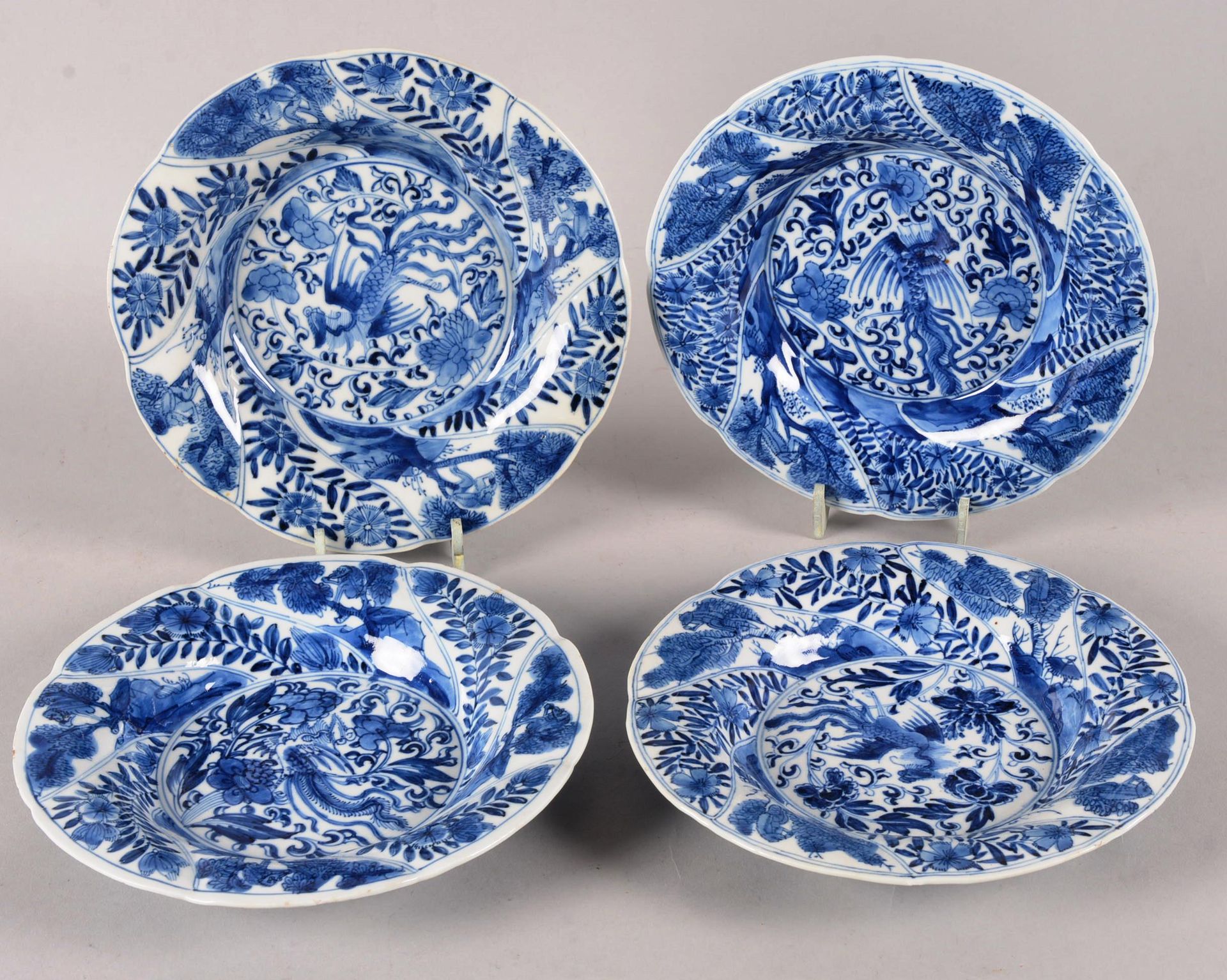 Suite de quatre assiettes. Chine 中国。

一套四个瓷盘，以蓝色釉下彩装饰，在花的背景上有凤凰在飞翔，花枝和伞形松树被框在卡口中&hellip;