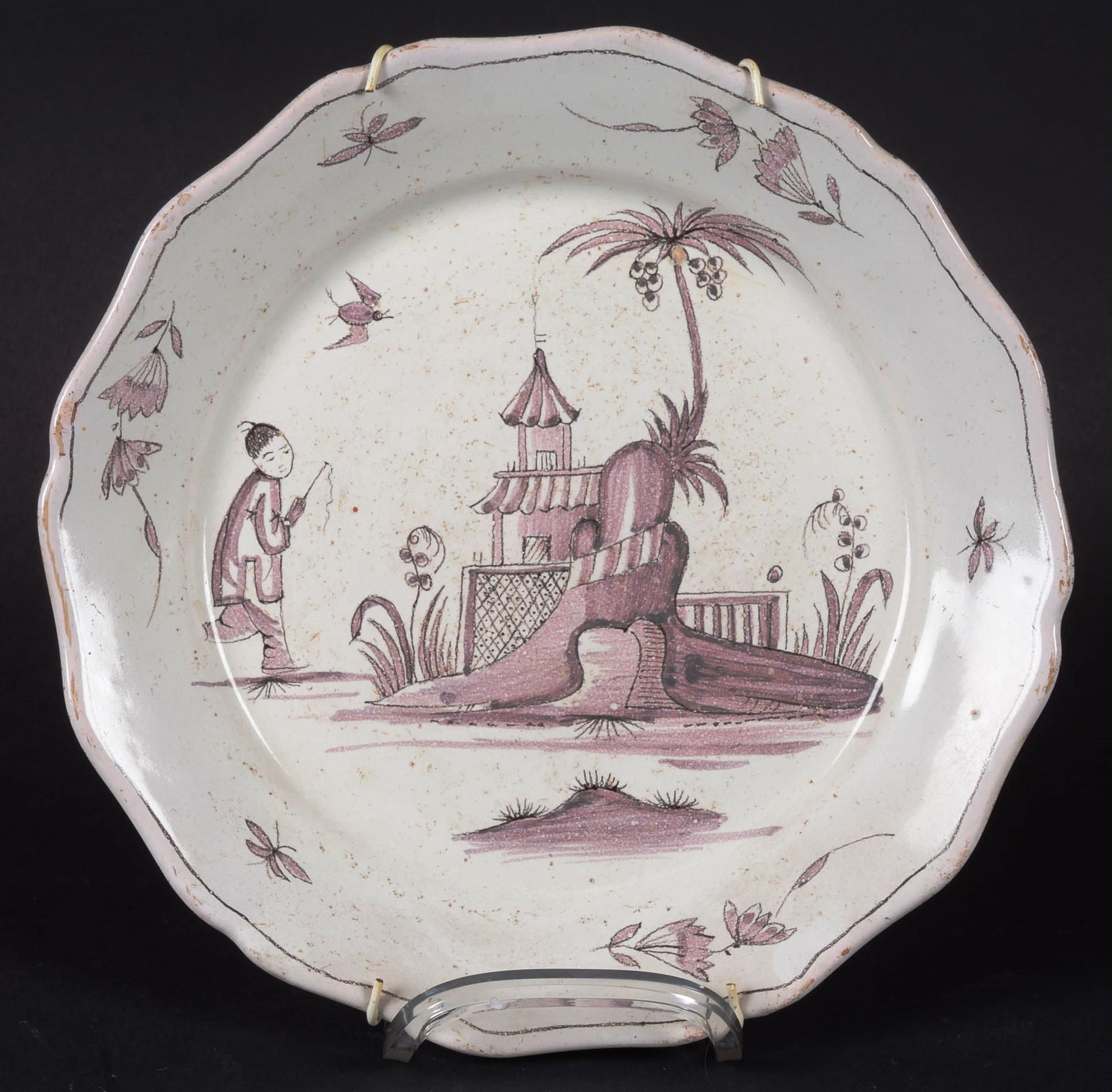 SAINT - OMER.Assiette 圣-欧麦尔。

陶器盘子，有一个轮廓的边框，用锰紫色装饰，上面有一个中国人在有棕榈树的宝塔前。

18世纪。

直径&hellip;