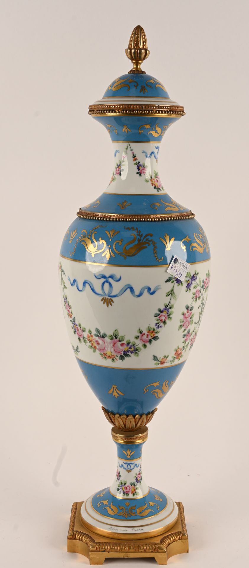 Dans le goût de Sèvres. 塞夫勒风格。
一个大的有盖瓷瓶，在白色和蓝色的背景上装饰着镀金的交错和花卷。鎏金青铜制的脚、环和格子。
高度：6&hellip;